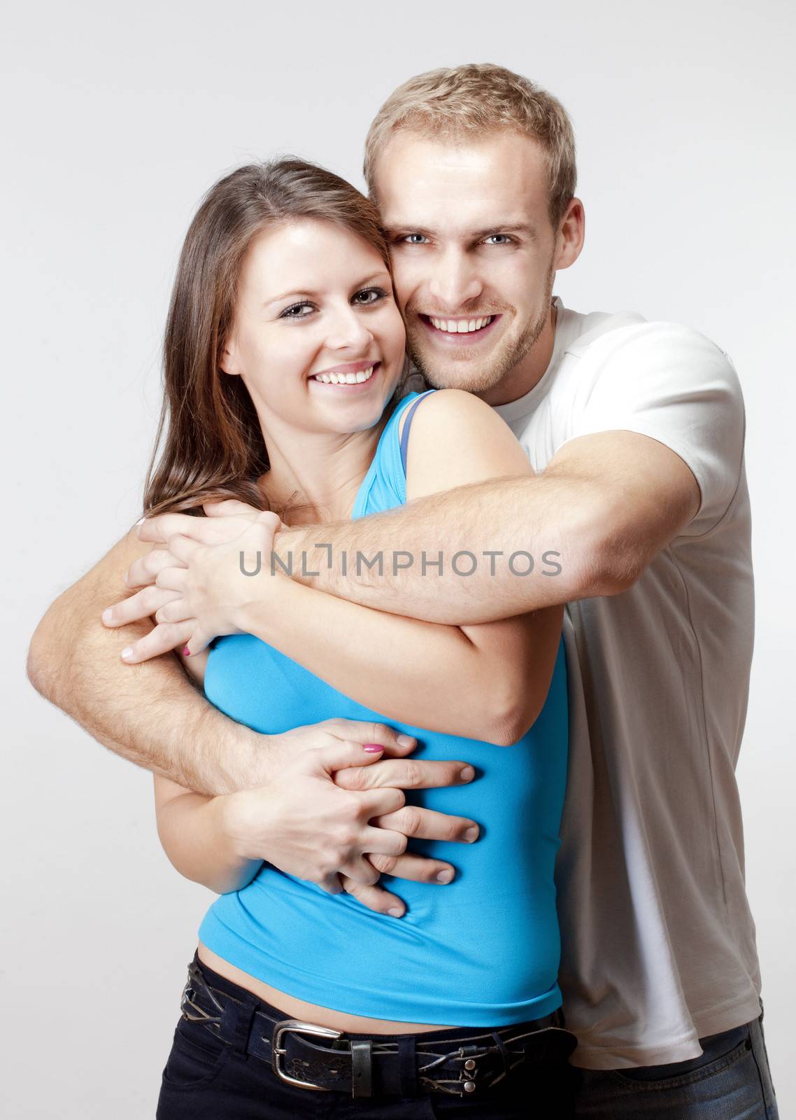 portrait of a happy young couple smiling, looking - isolated on light gray