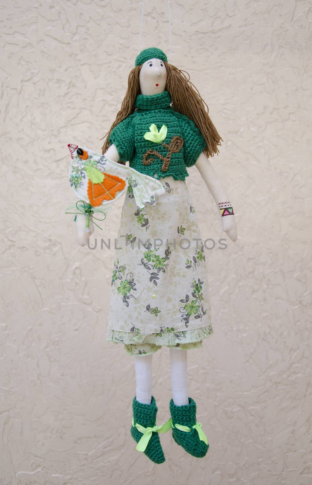 The Handmade doll with a bird on the hand in a dress and sweater on a string
