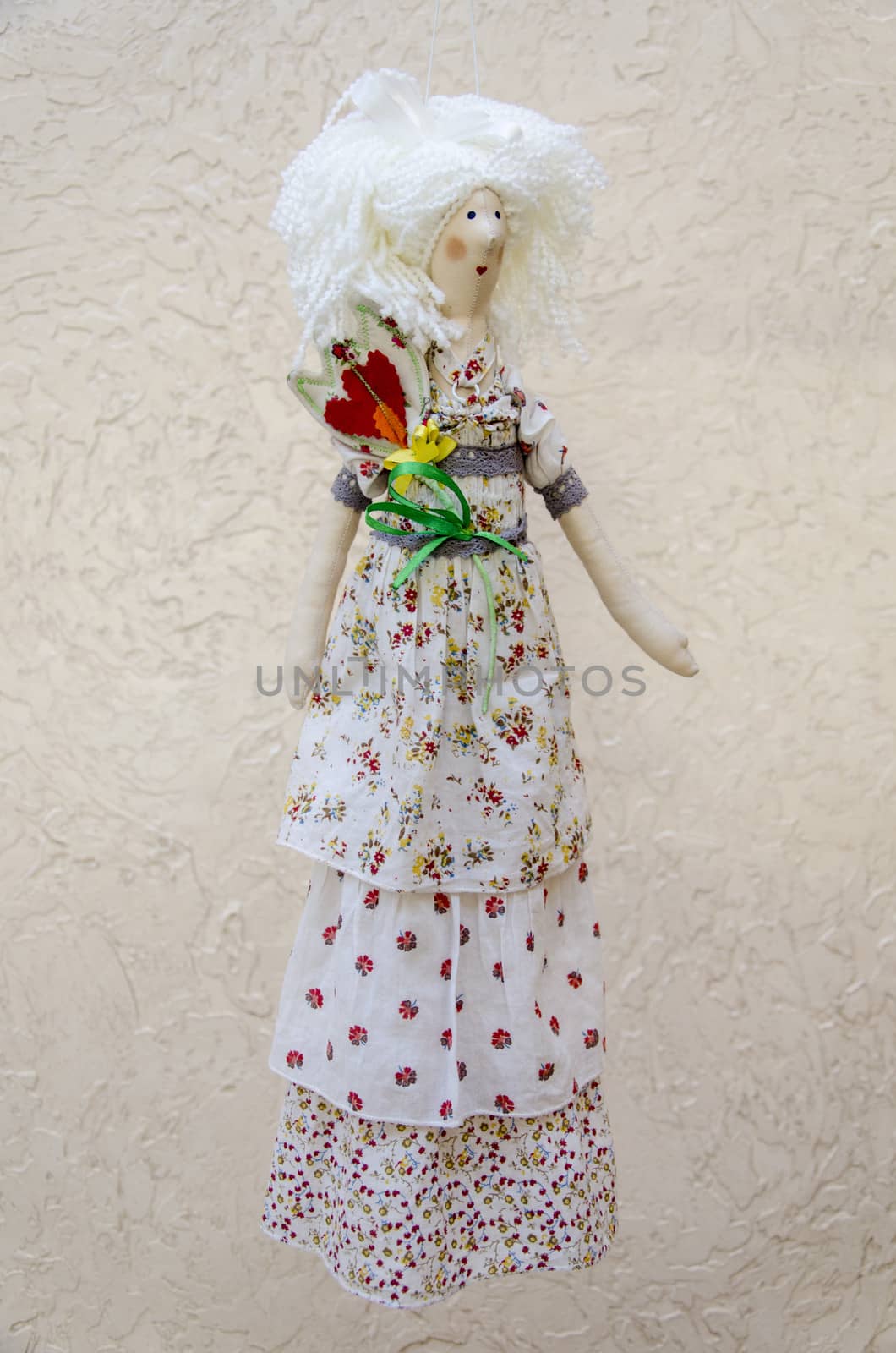 The Handmade doll with a flower in his belt in a long white dress on a string