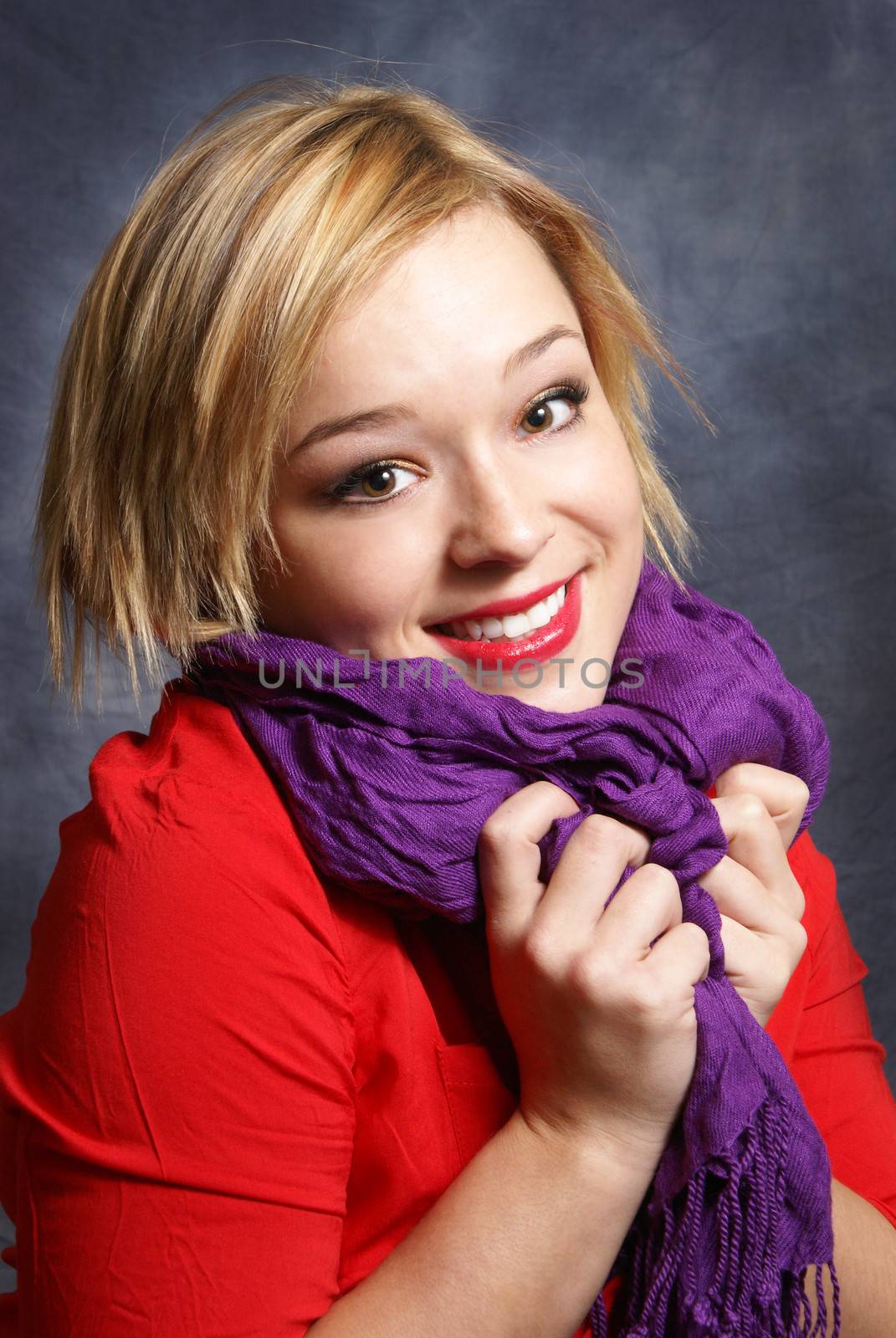 A young woman scrunches her scarf in a warm fashionable pose.