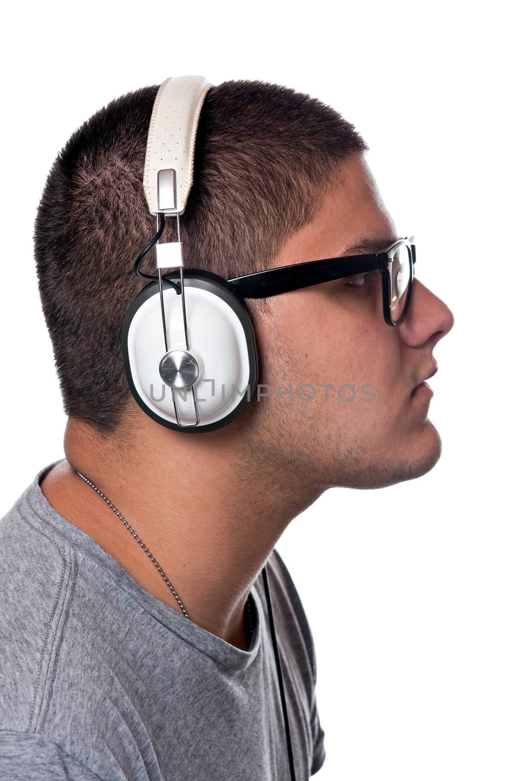 A young man listens to music with a set of head phones over a white background.