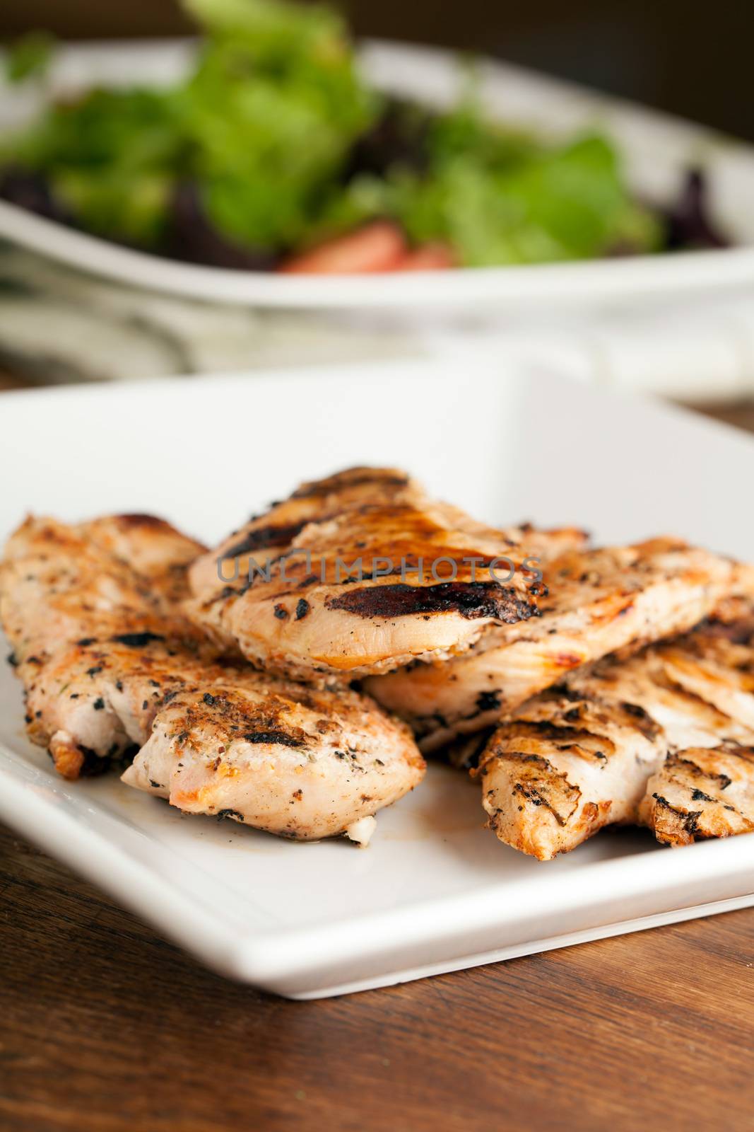 Freshly prepared grilled chicken breasts and salad ingredients.