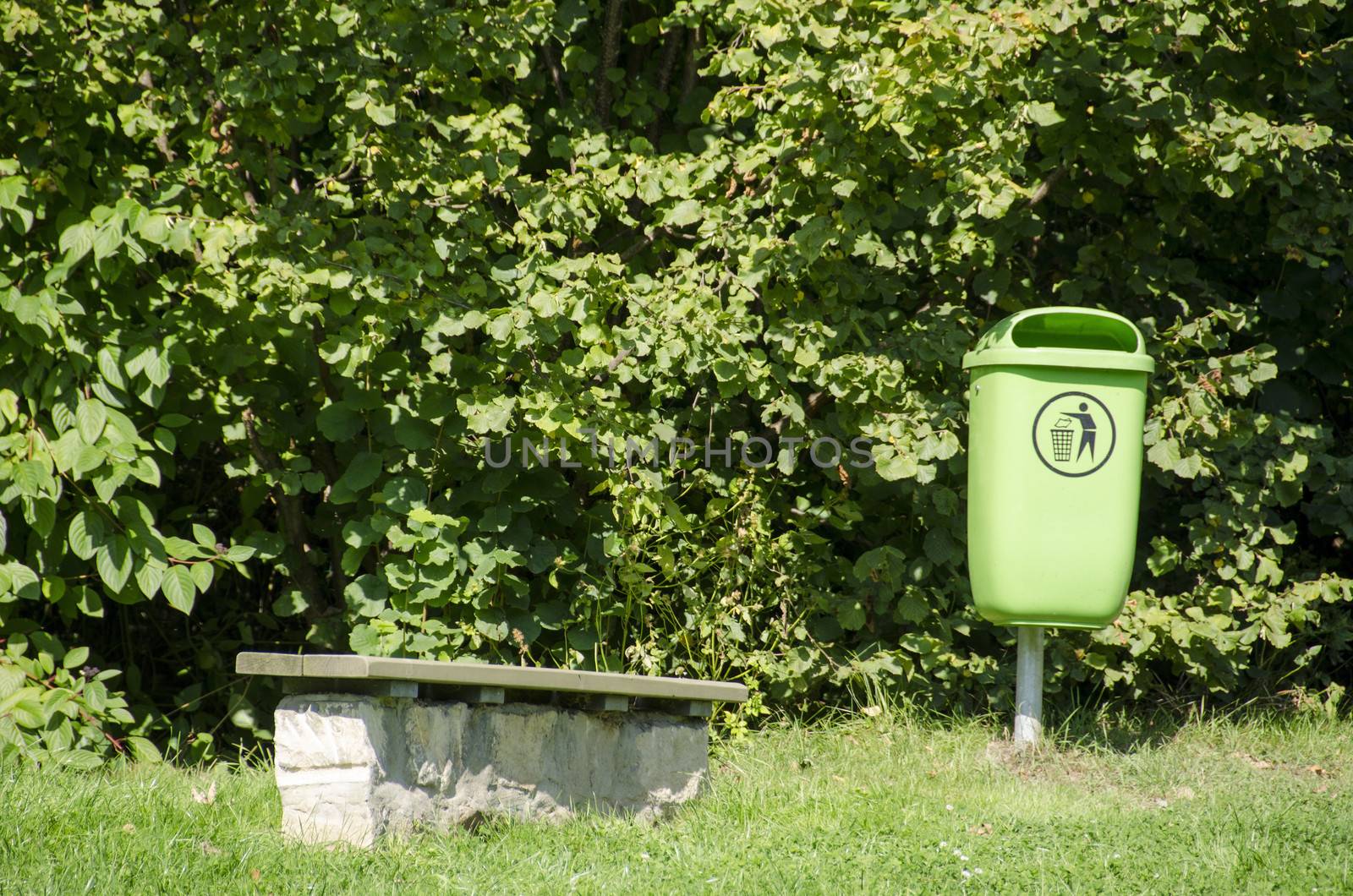 Green waste bin in a park with a park bench