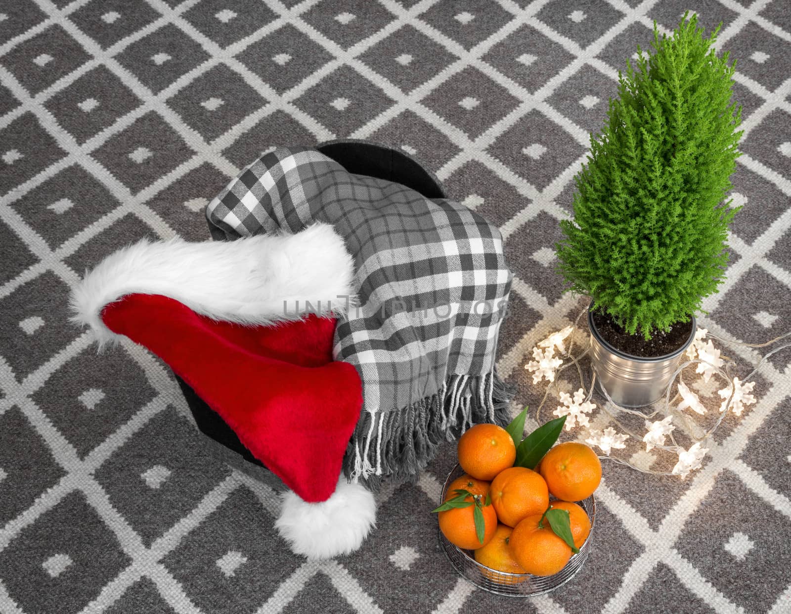 Christmas composition. Santa hat, lights, checked plaid, clementines, and little green tree.