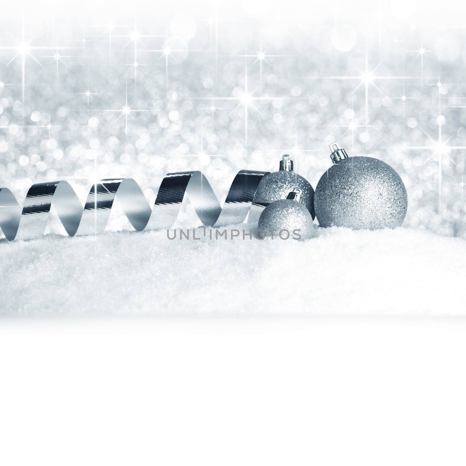 Christmas balls and ribbons on snow over shiny stars background