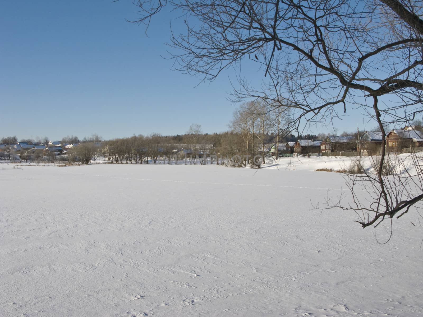Frozen lake, small village, sunny winter day