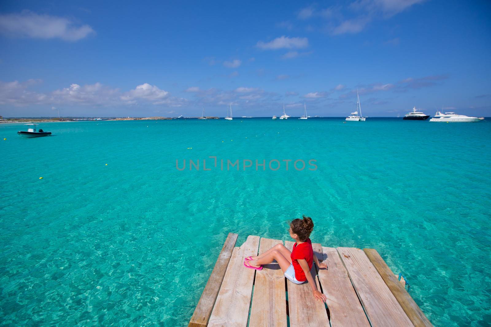 Kid girl looking at tropical Mediterranean sea from wood pier by lunamarina