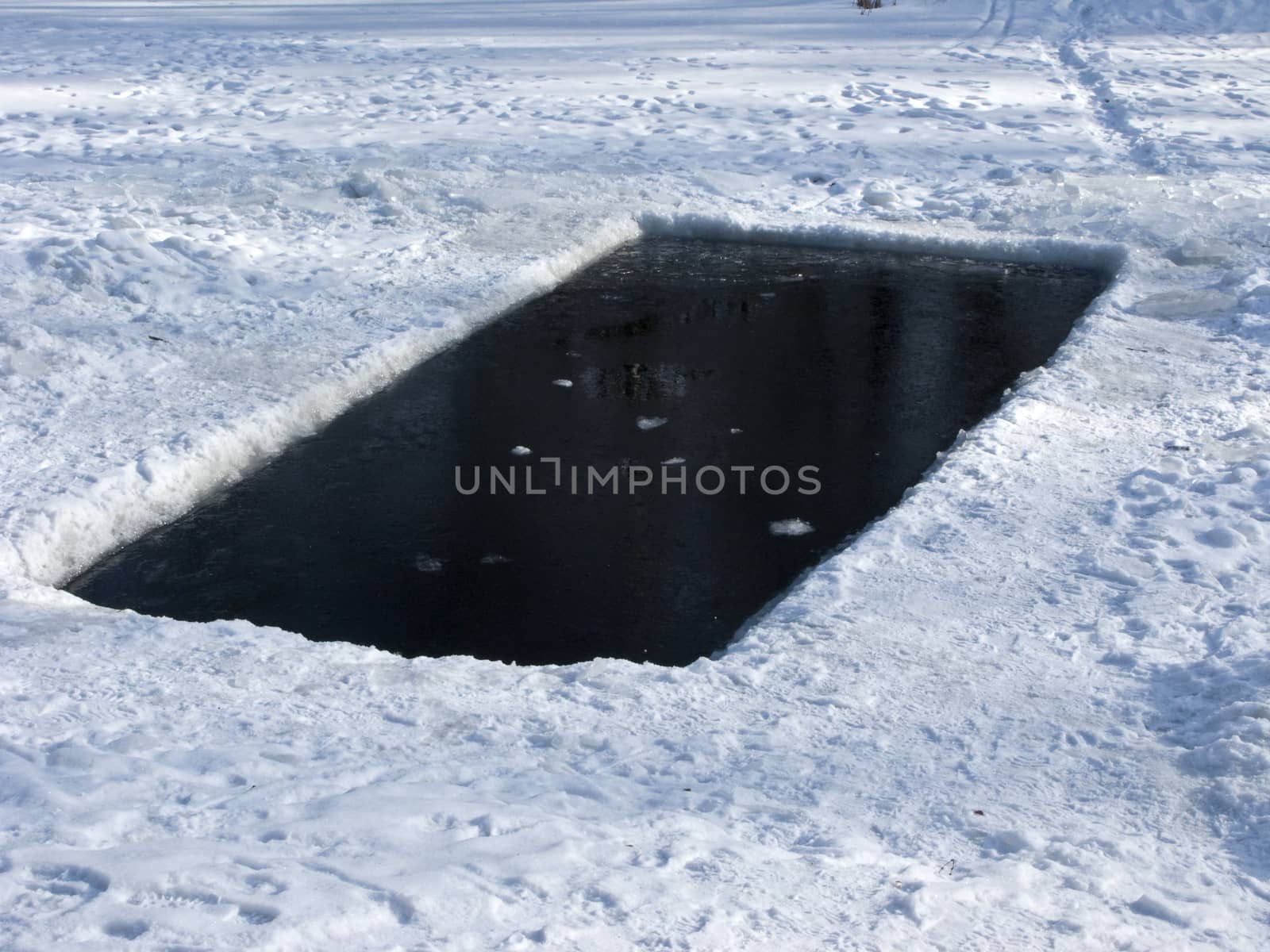 Square ice hole in frozen pond, Russia