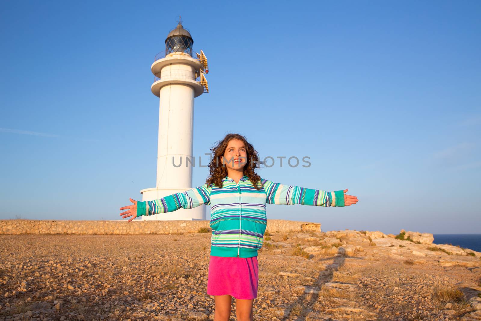 Happy open arms kid girl in Mediterranean lighthouse at formentera