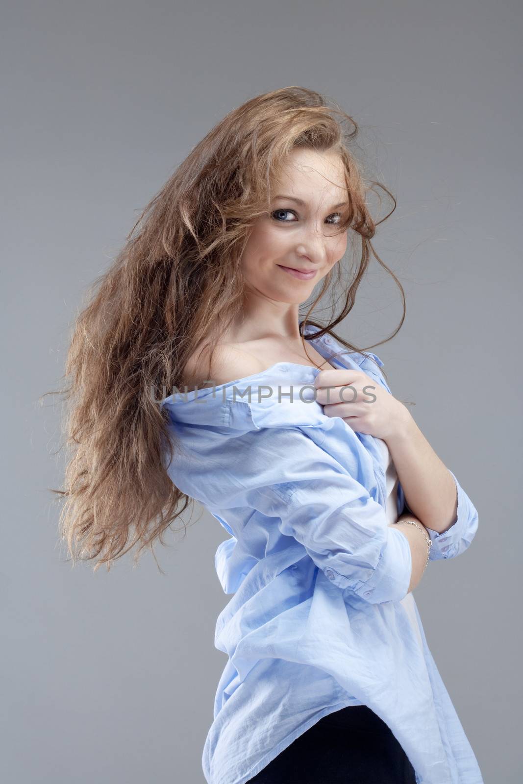 portrait of a young beautiful woman with brown hair smiling - isolated on gray