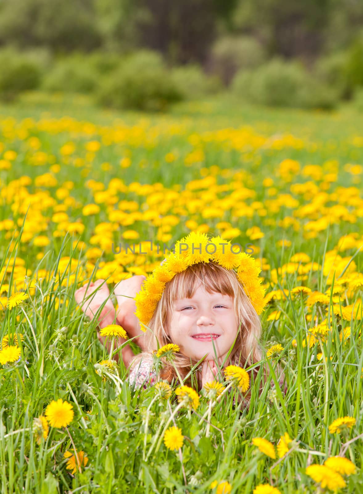 Portrait of cute little girl with dandelion wreath enjoying a summer day outdoors