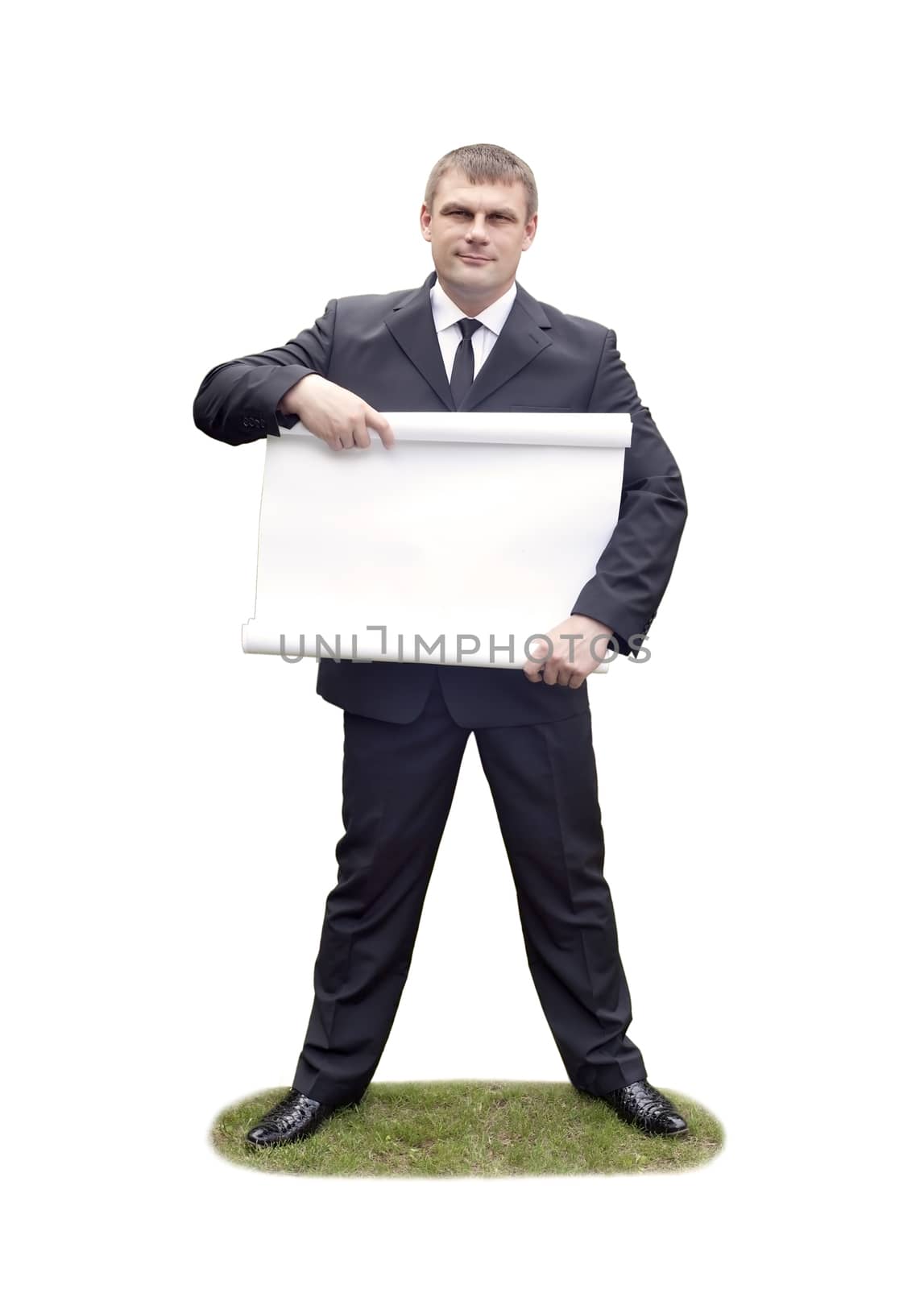 A man in a dark suit holding a sheet of ads and standing on the grass
