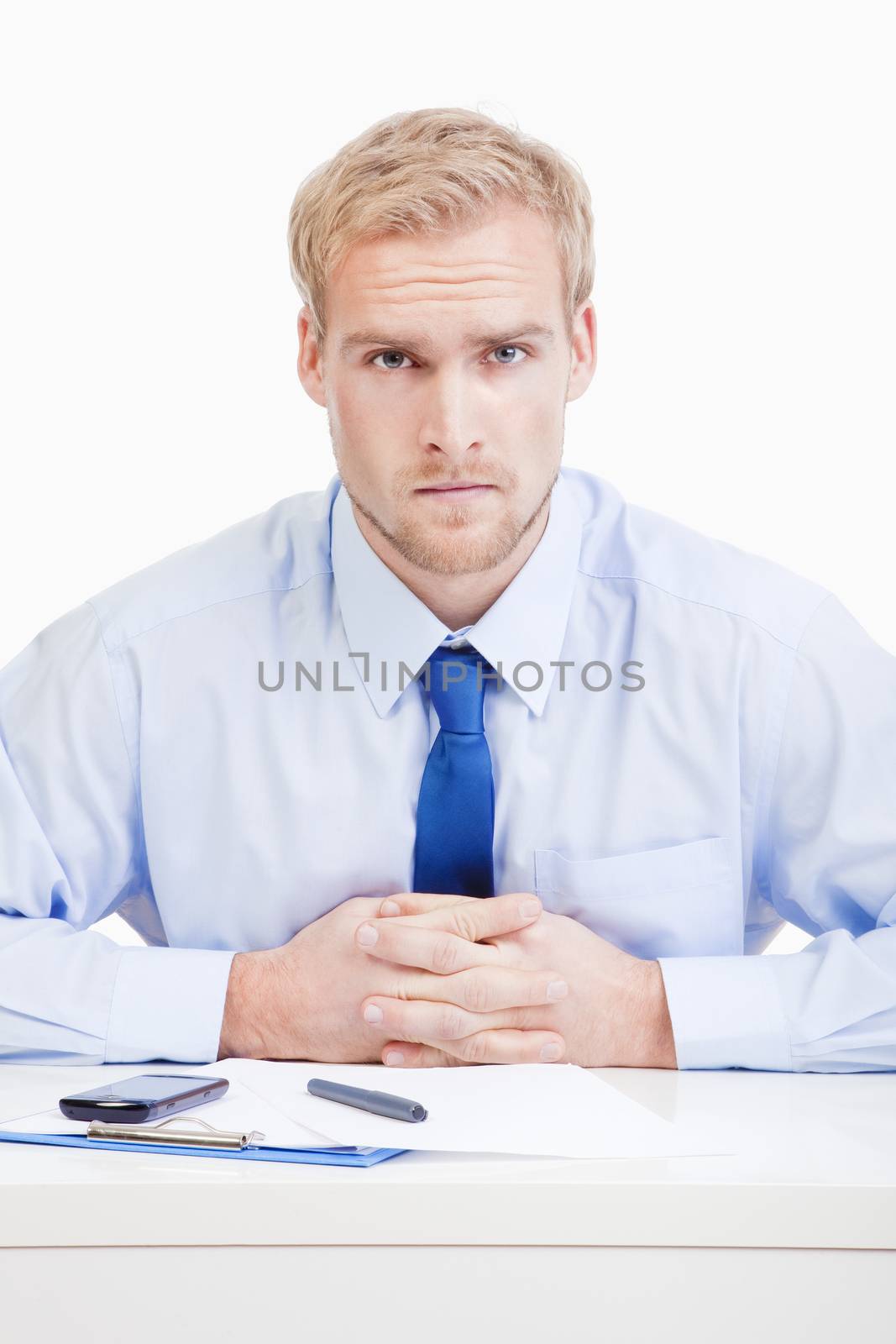 serious boss sitting behind desk at office looking at camera