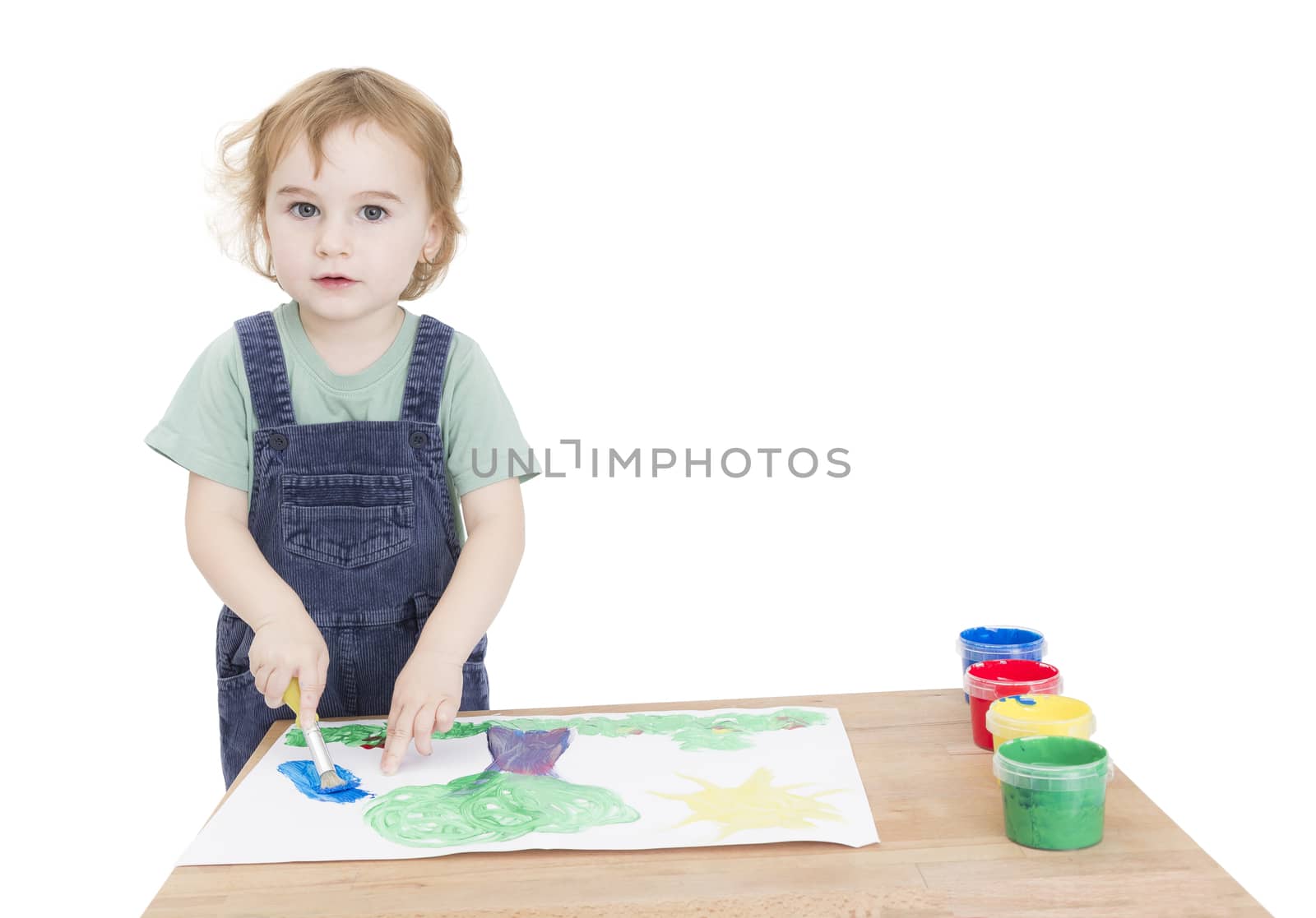 cute girl painting on small desk in grey background. studio shot