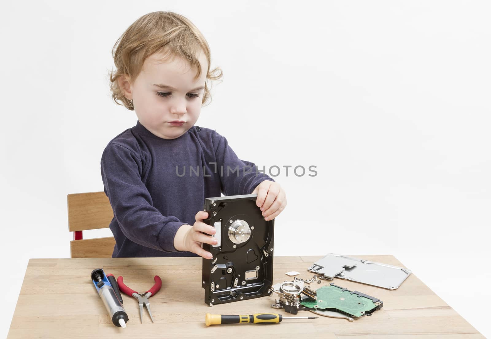 young child repairing open hard disk drive with different tools