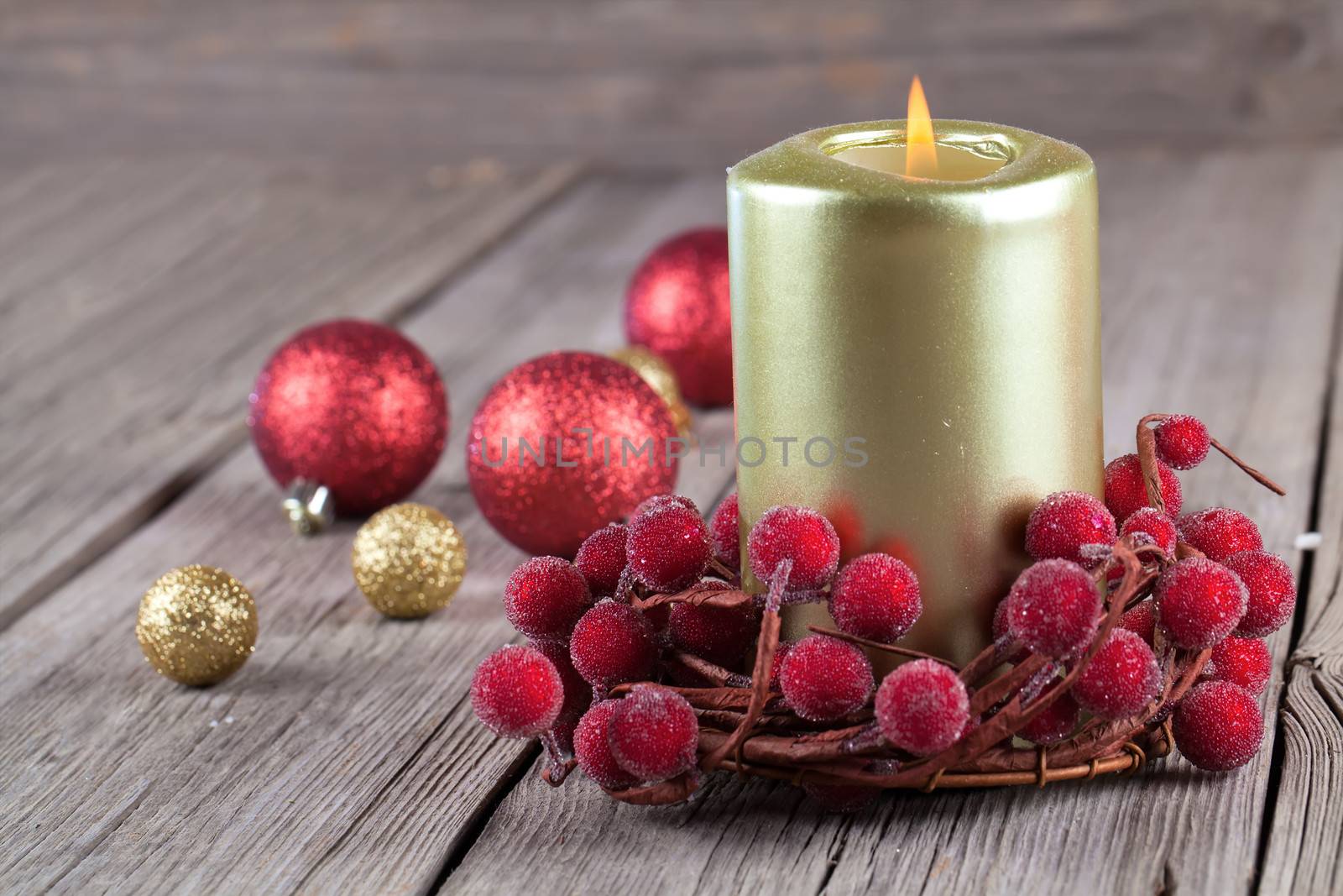 Christmas wreath from red berries with a candle on wooden background
