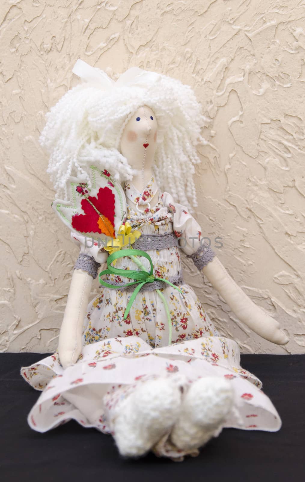 The Handmade doll with a flower in his belt in a long white dress sitting