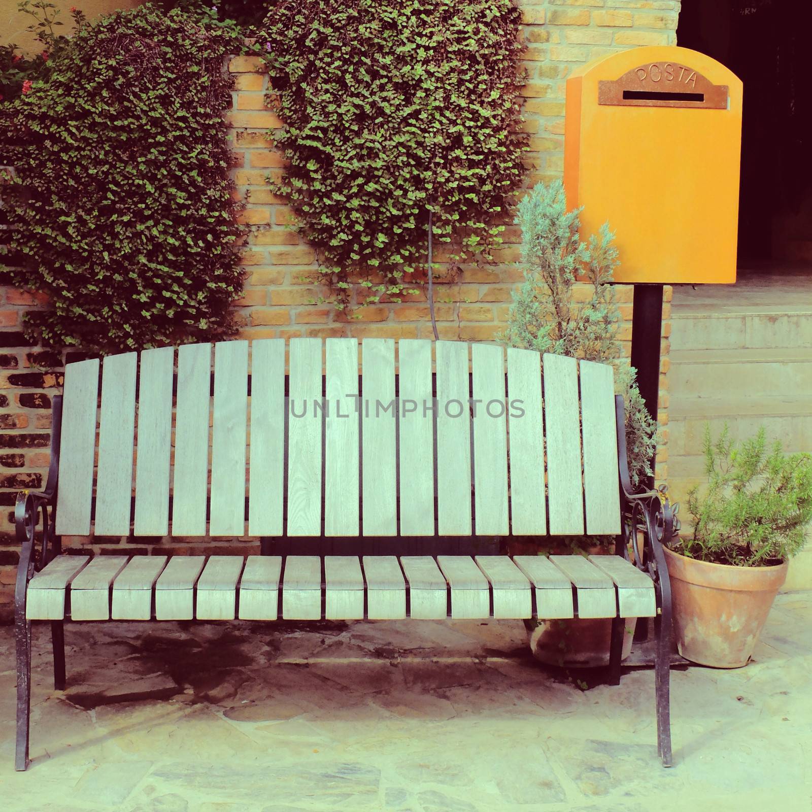 Wooden chair with vintage mailbox in garden, retro filter effect