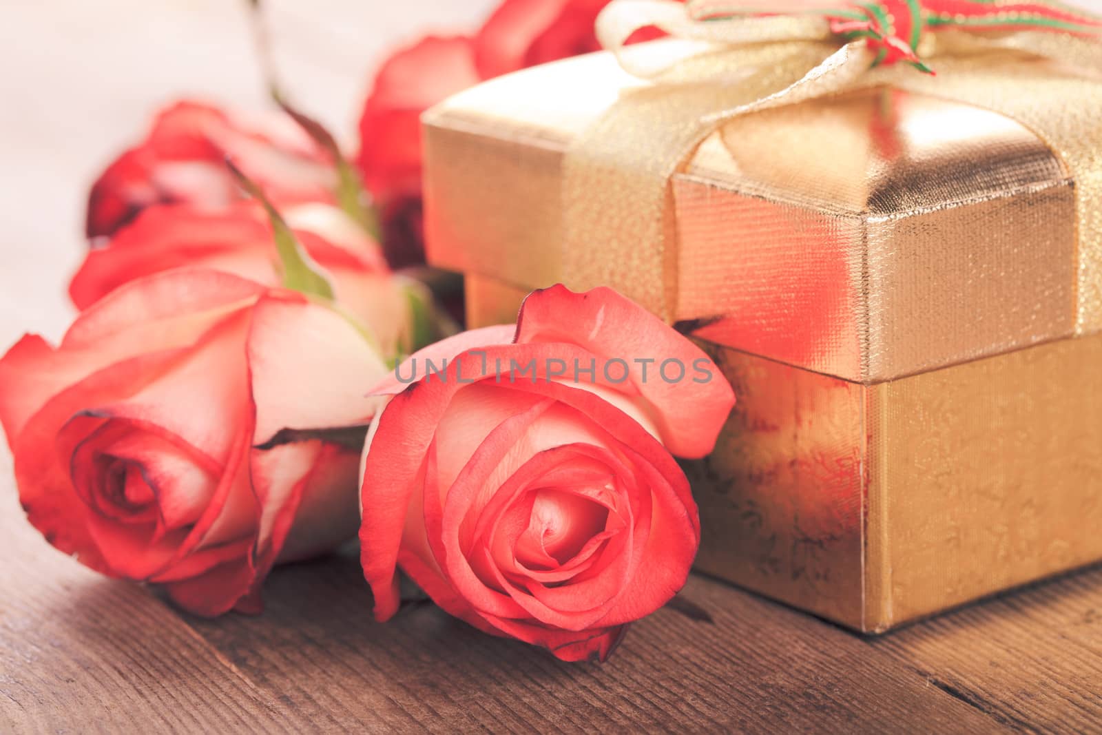 Golden gift box and bouquet of roses on the table