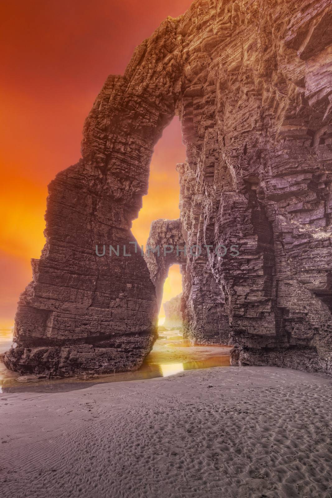 Stone arch on Playa de Las Catedrales, on a sunset. Spain