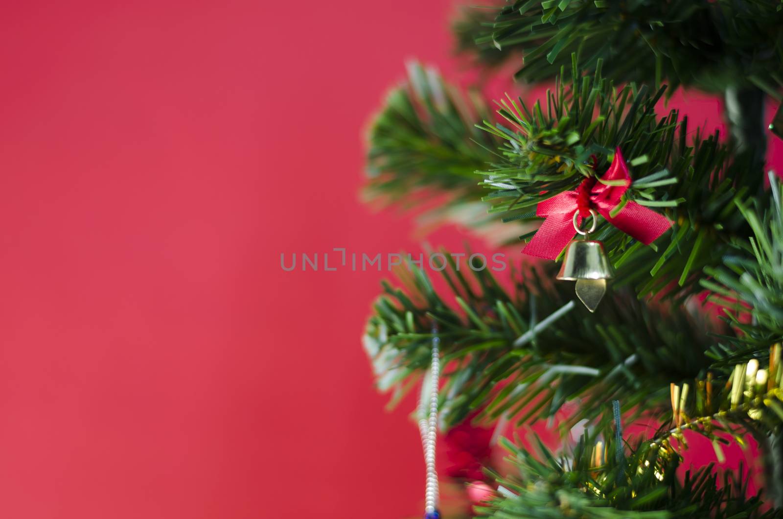 close up small bell on christmas tree on red background