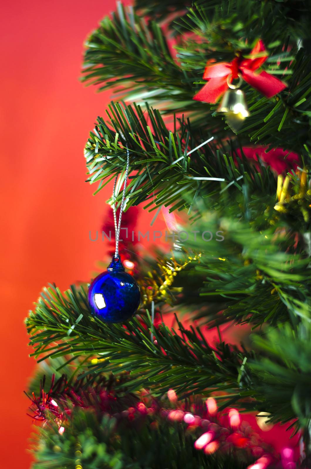 close up blue christmas ball on tree on red background