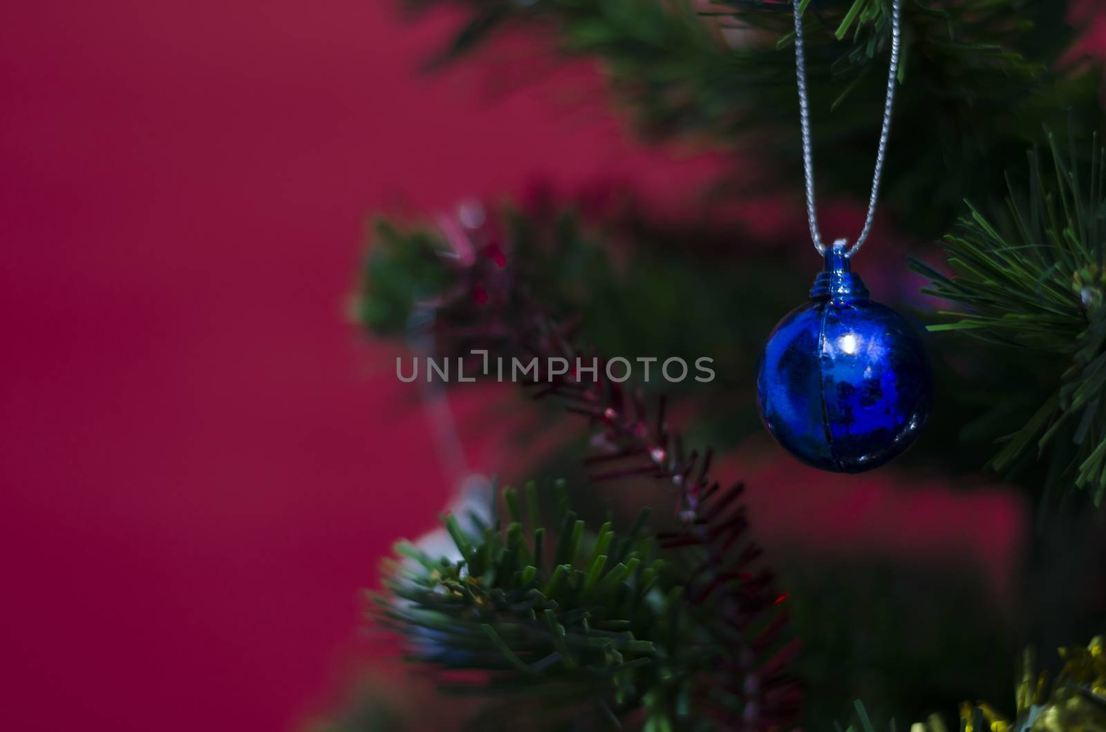 close up blue christmas ball on tree on red background