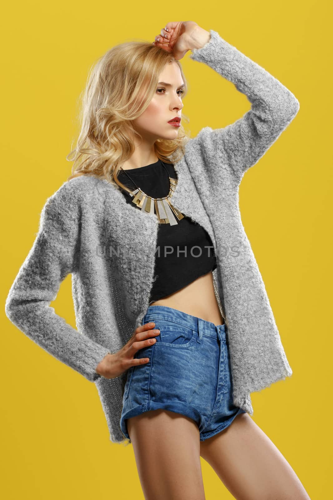 Beautiful blond model in shorts and a t-shirt on a yellow background