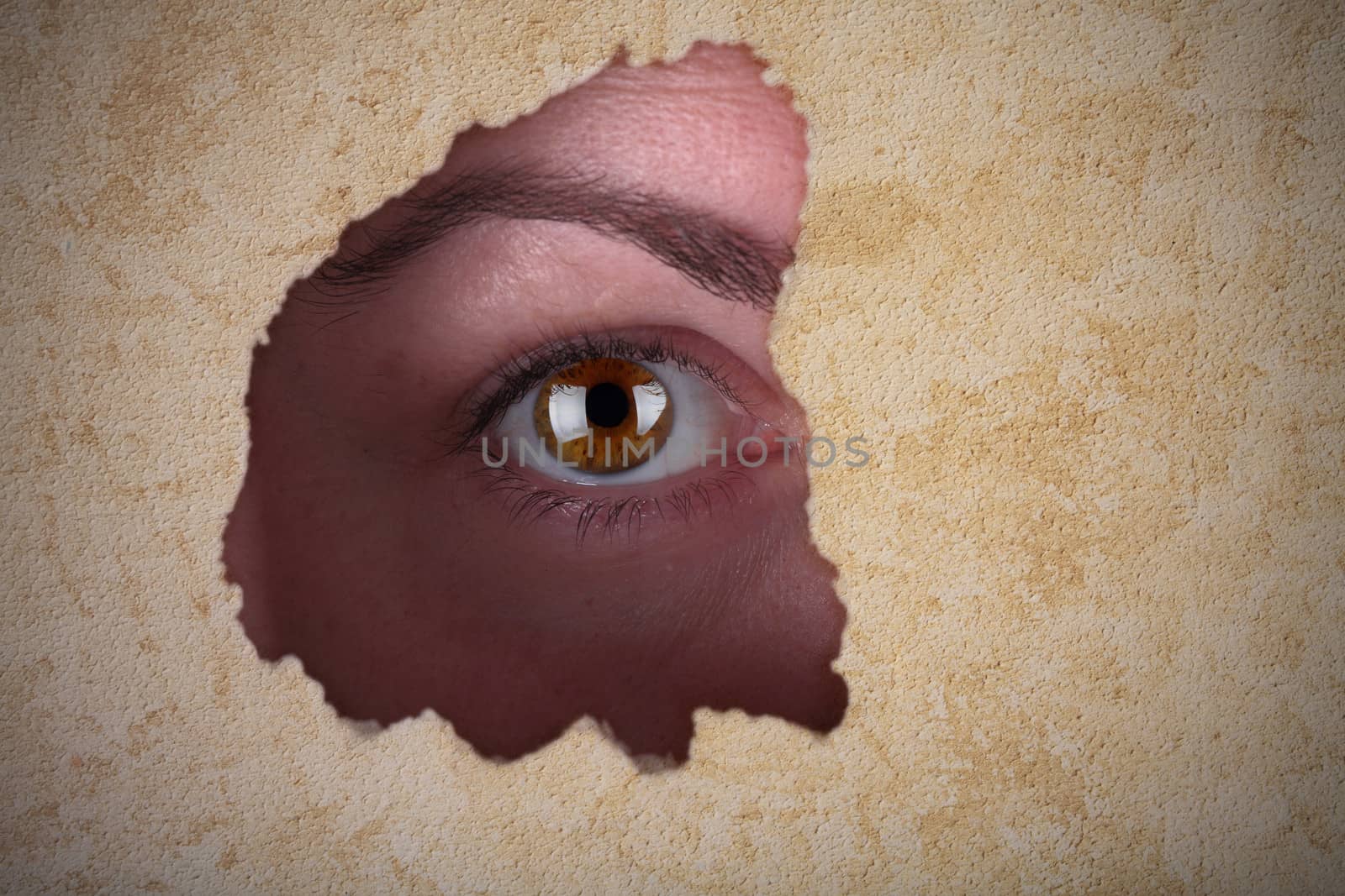 eye of a woman looking through a hole in the wall