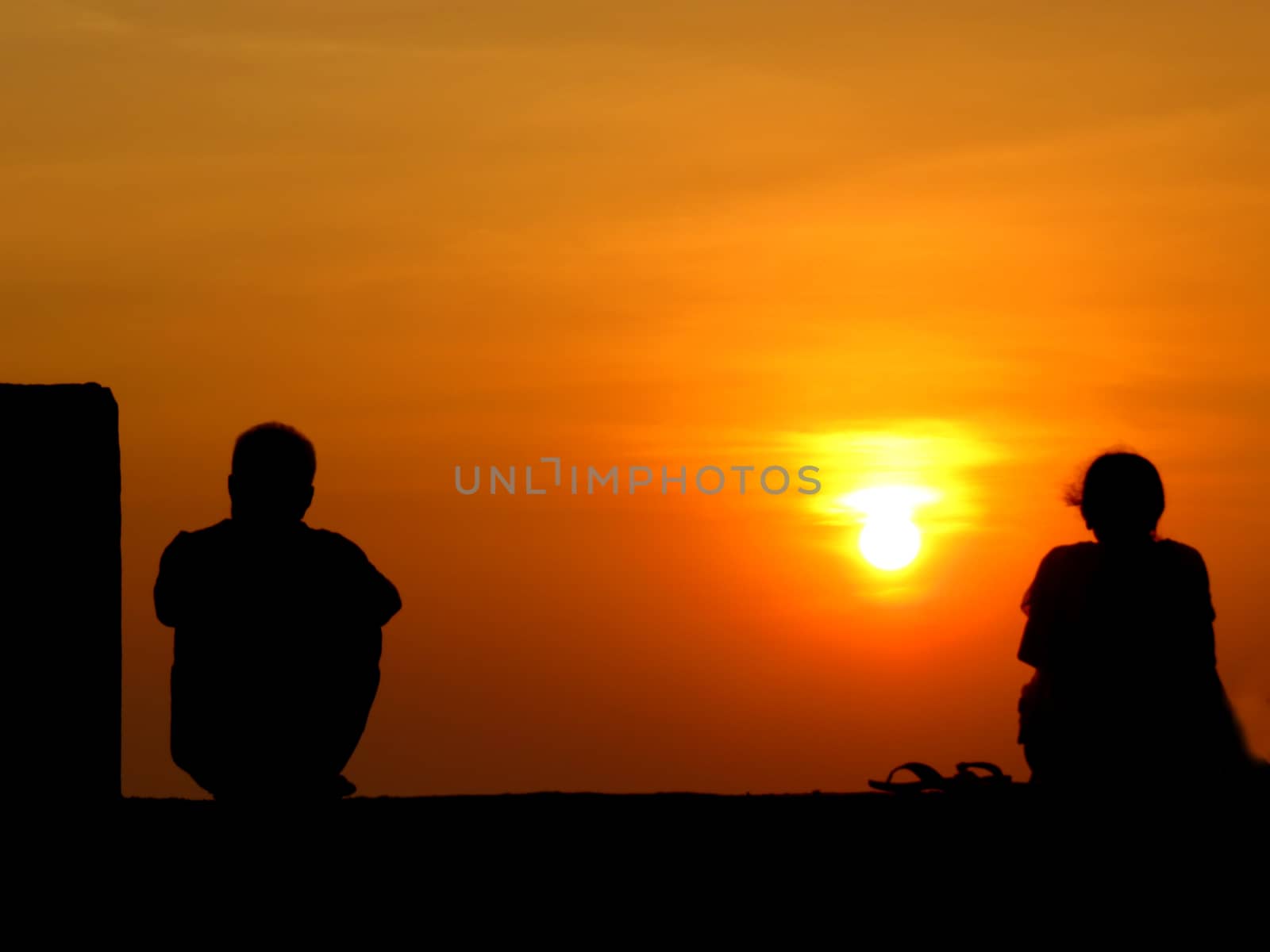 A metaphorical image of the silhouettes of a seperated couple on the backdrop of a sunset.                               
