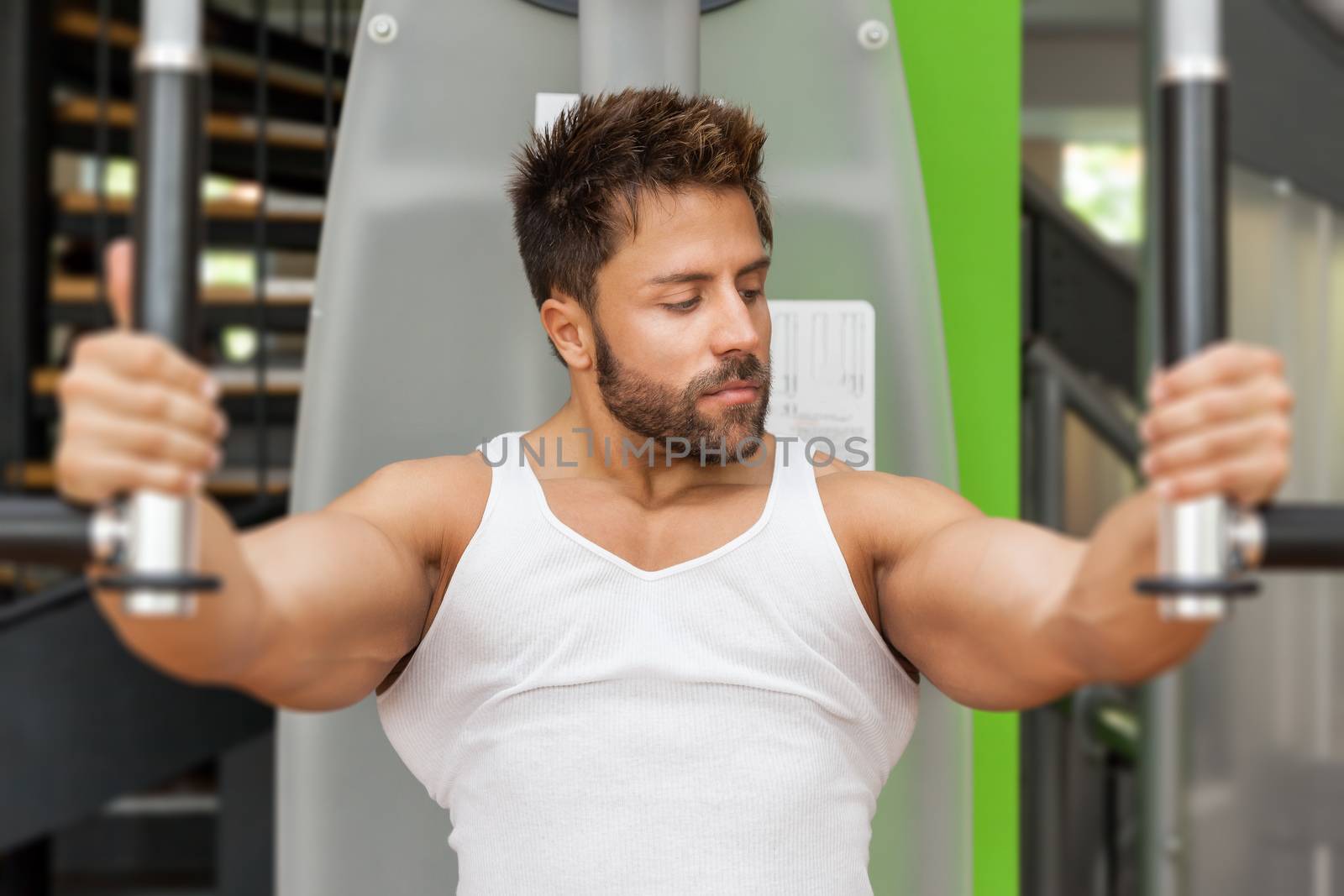 A handsome young muscular sports man doing butterfly exercise