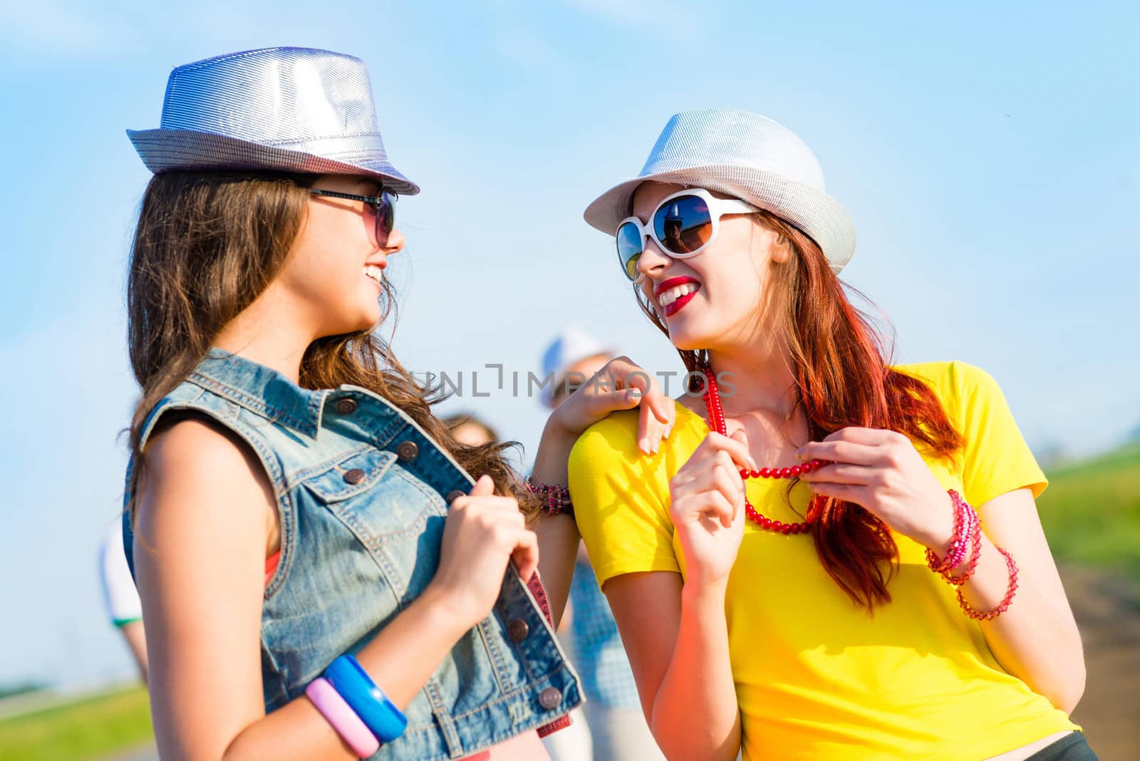 Two young girlfriends having fun on the background of blue sky and friends
