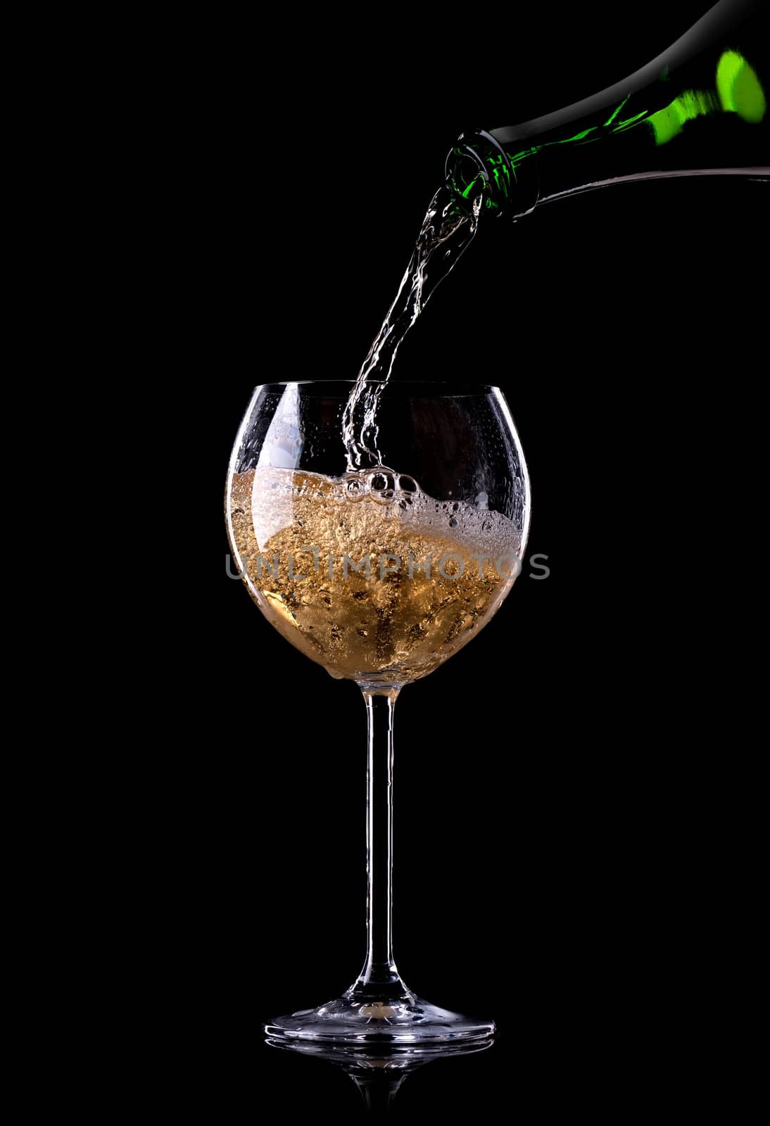 Champagne pouring from bottle into a glass on black background