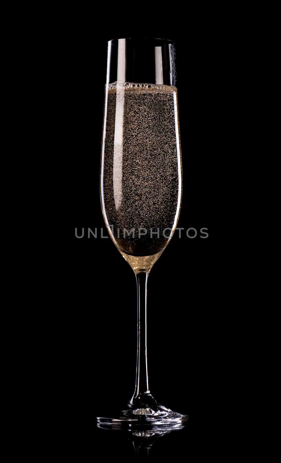 Glass of champagne with bubbles on black background