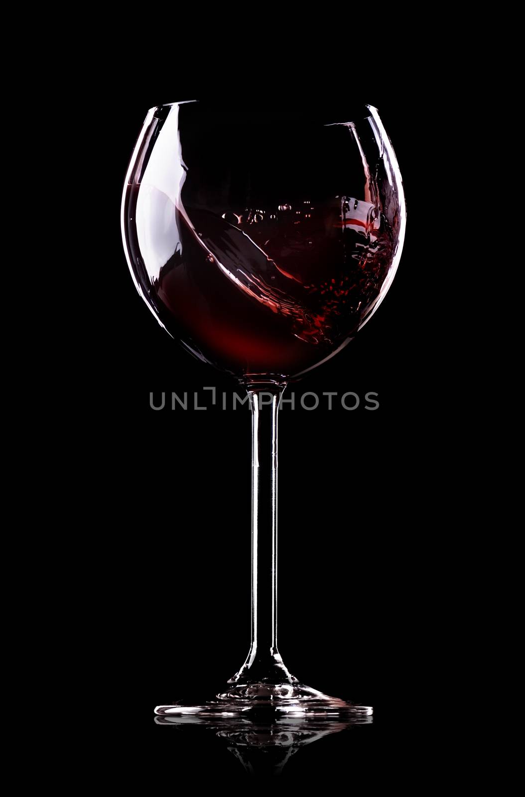 Wave of wine in wineglass on black background