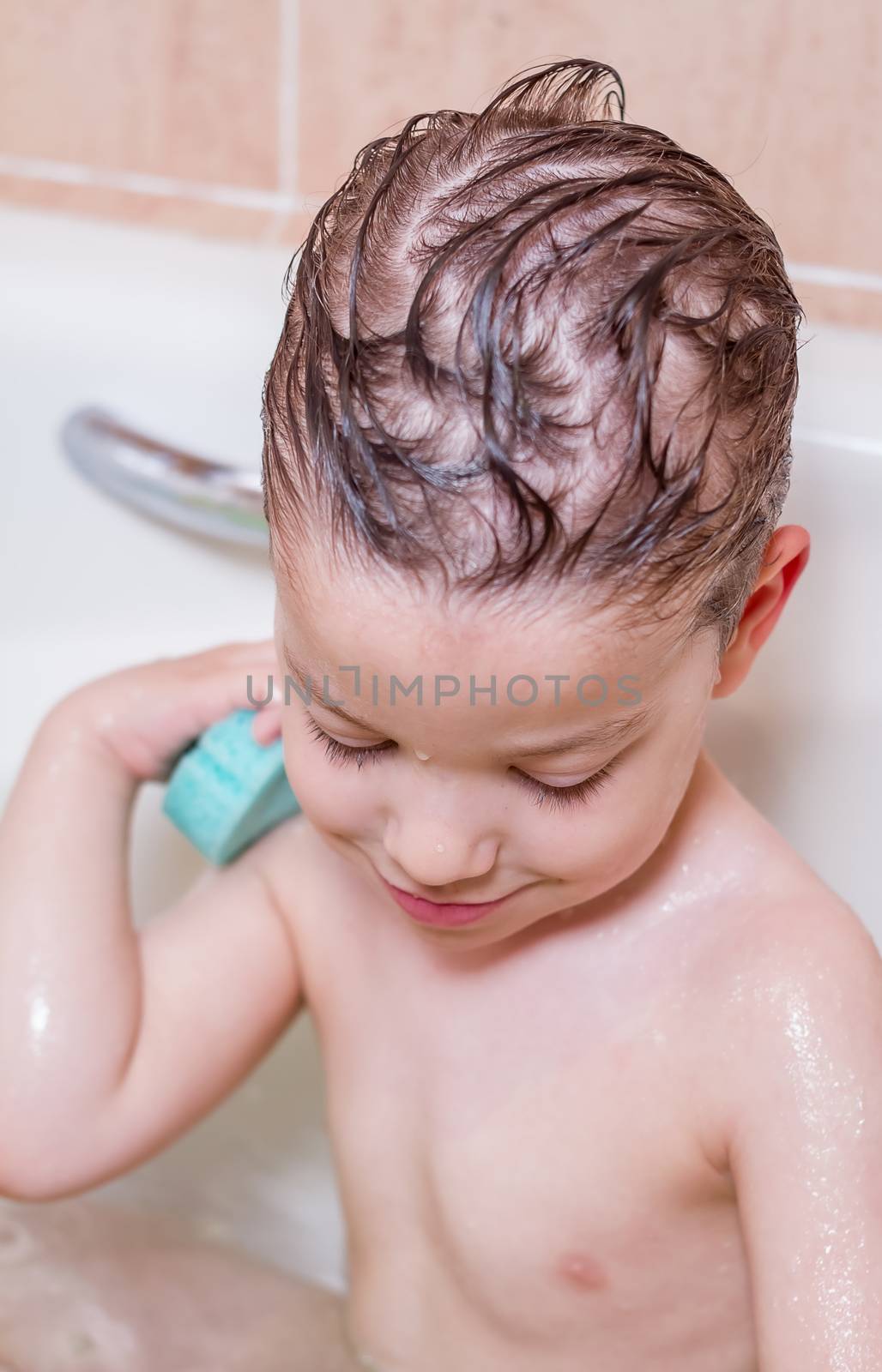 Cute boy happiness washing with sponge in a bathtub