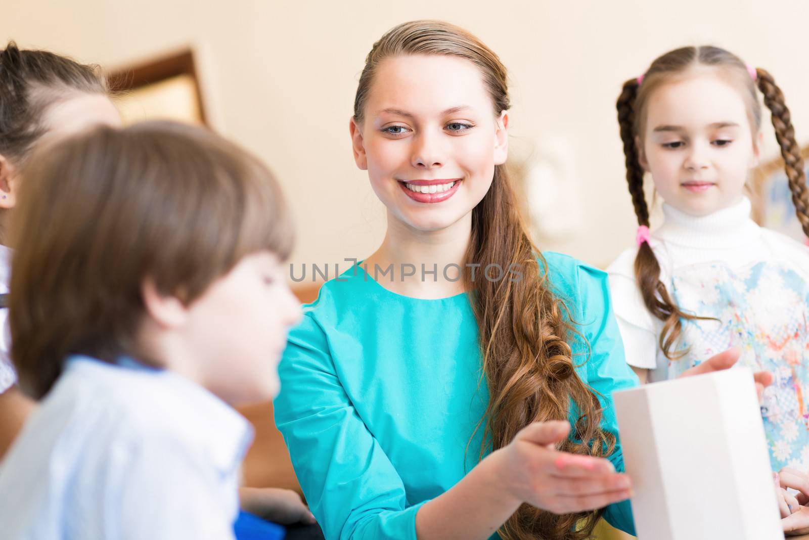 children with the teacher engaged in painting at an art school