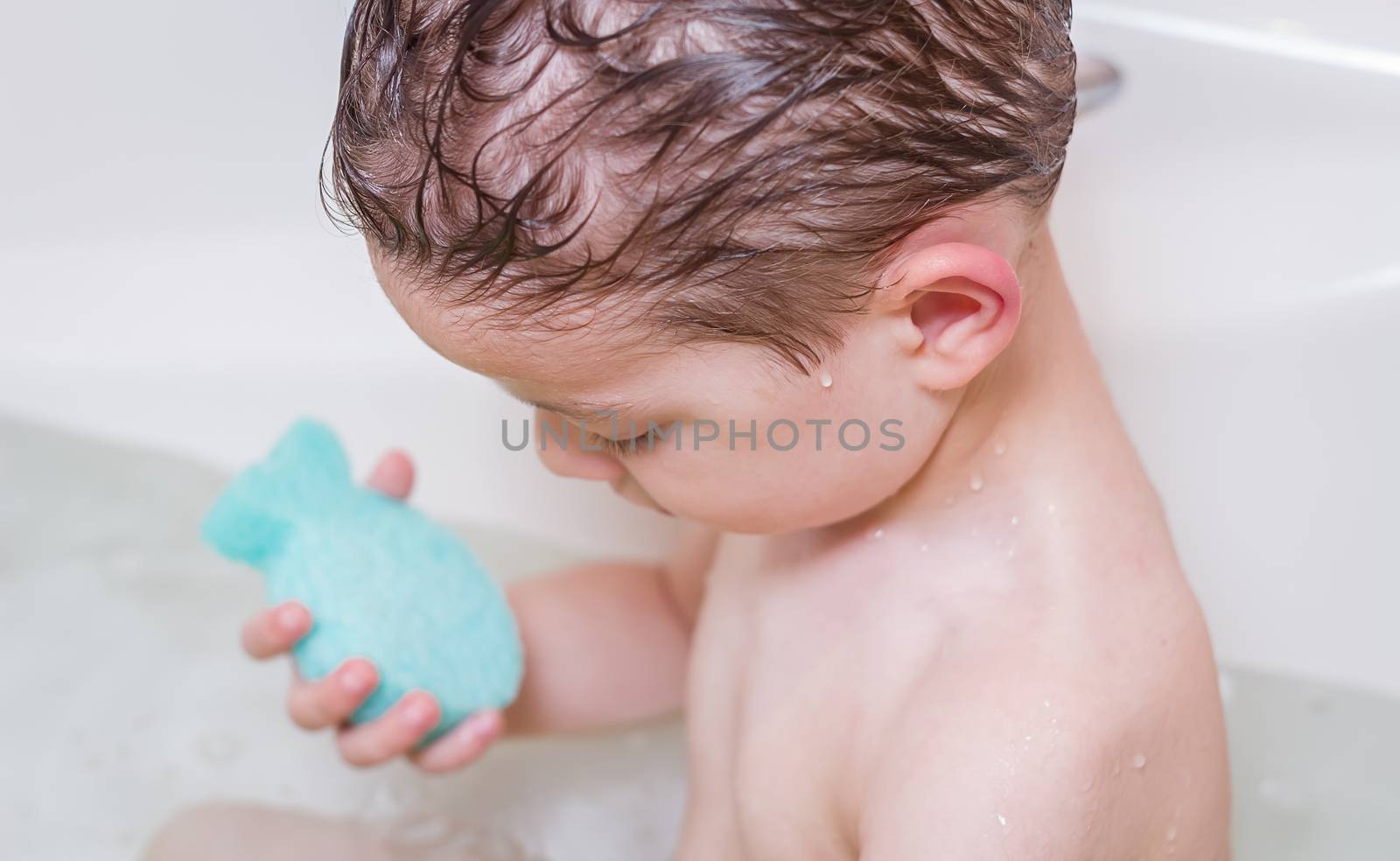 Cute boy happiness washing with sponge in a bathtub