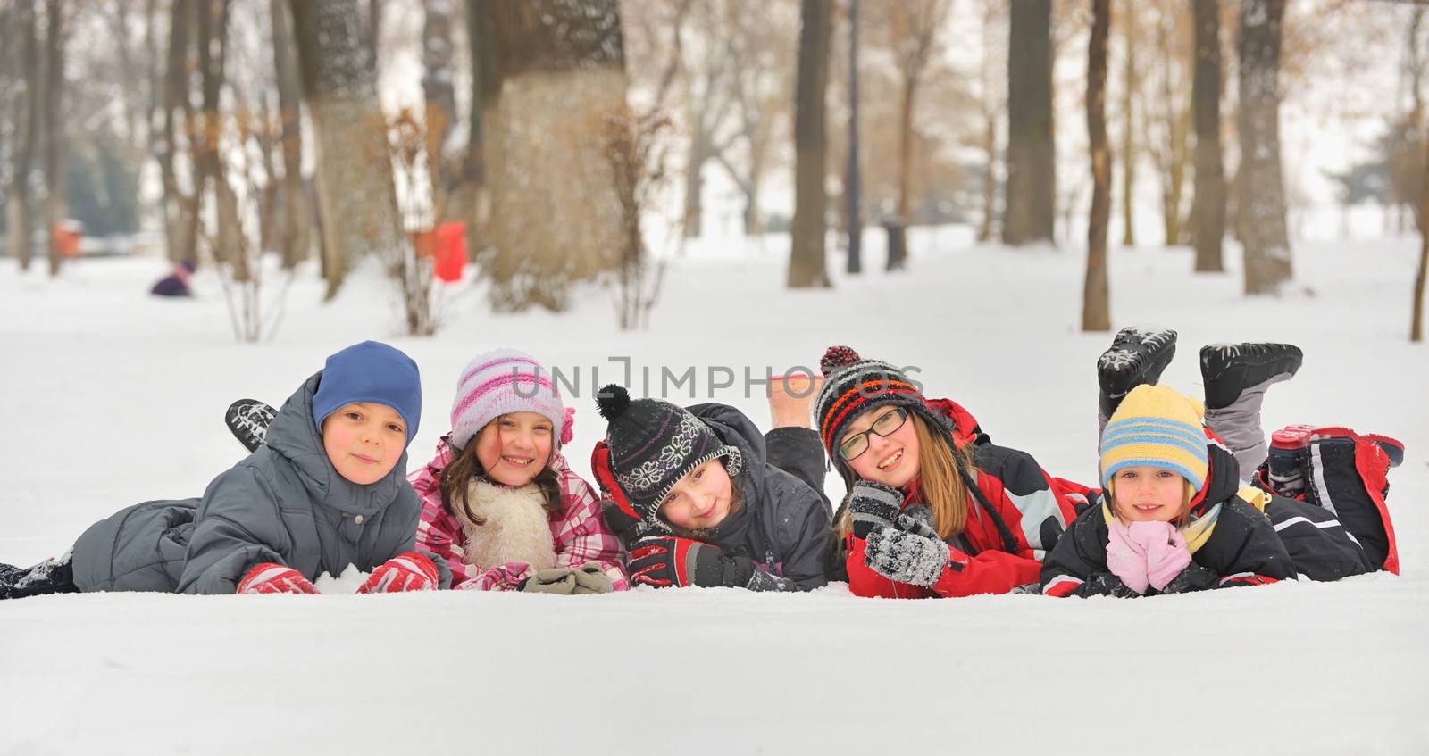 Group of children playing on snow in winter time