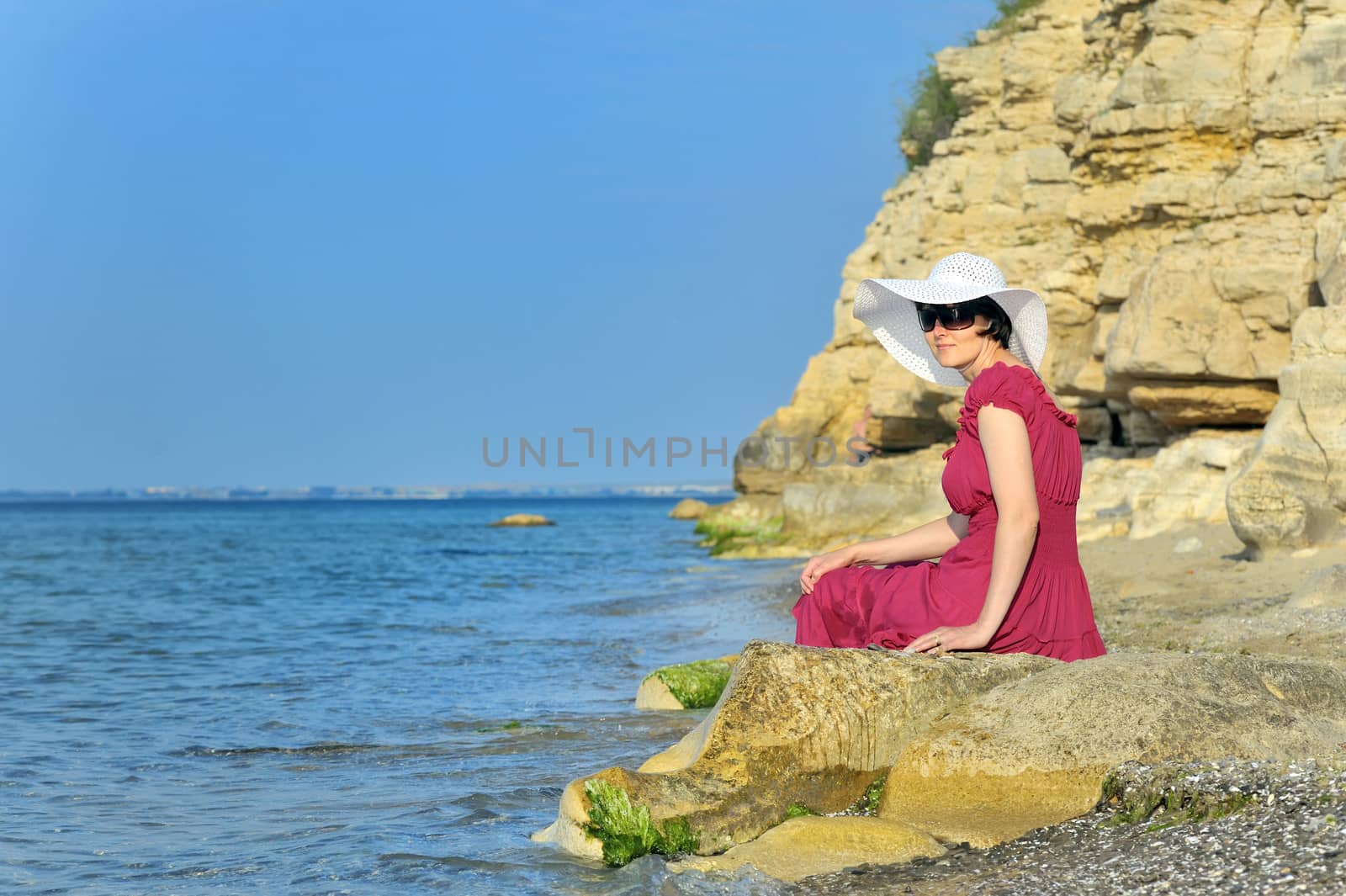 young woman portrait on the beach stand on the rock