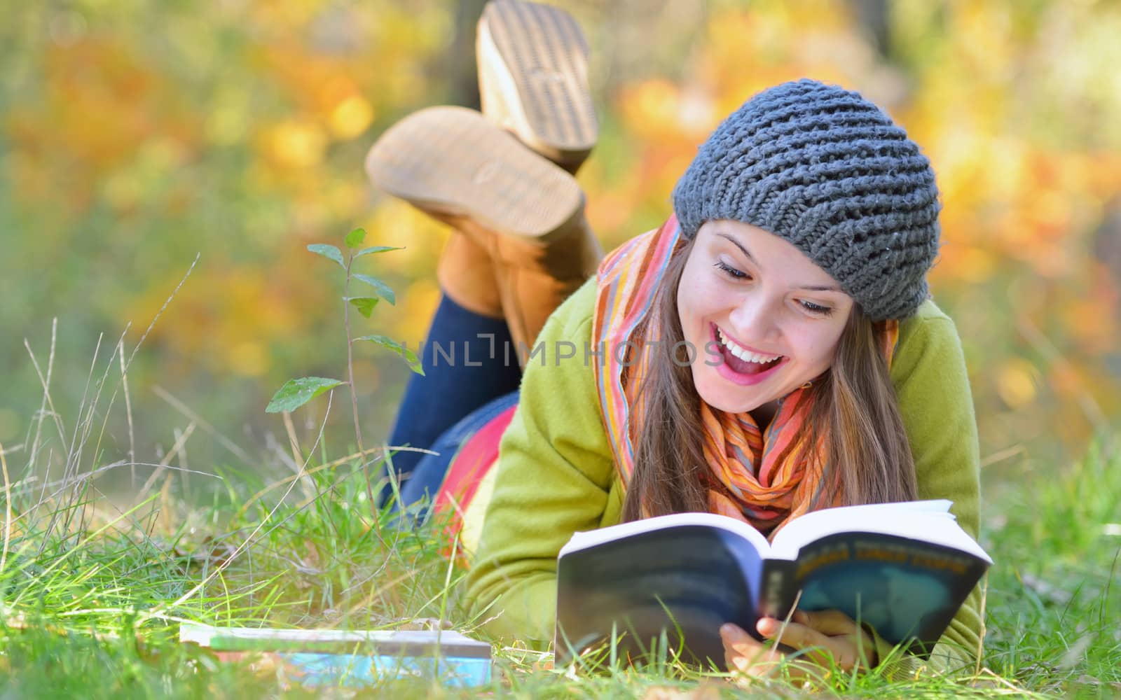 Beautiful young woman reading a book in autumn day