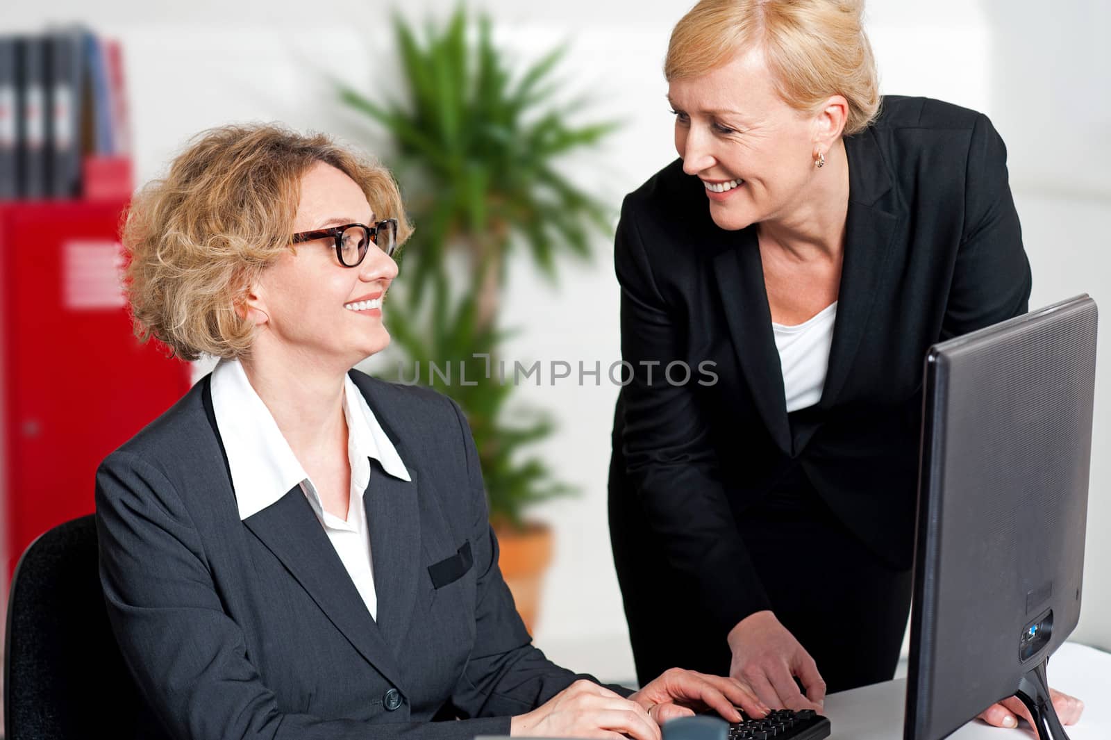 Two cheerful corporate women in office by stockyimages