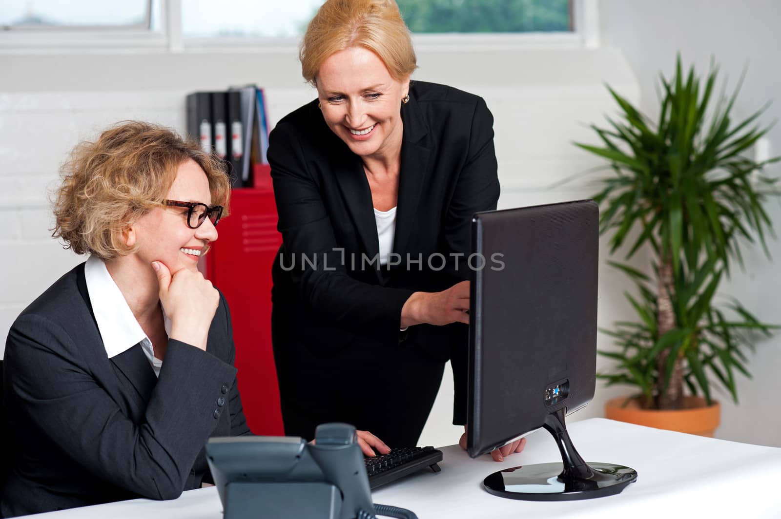 Two cheerful corporate women in office by stockyimages