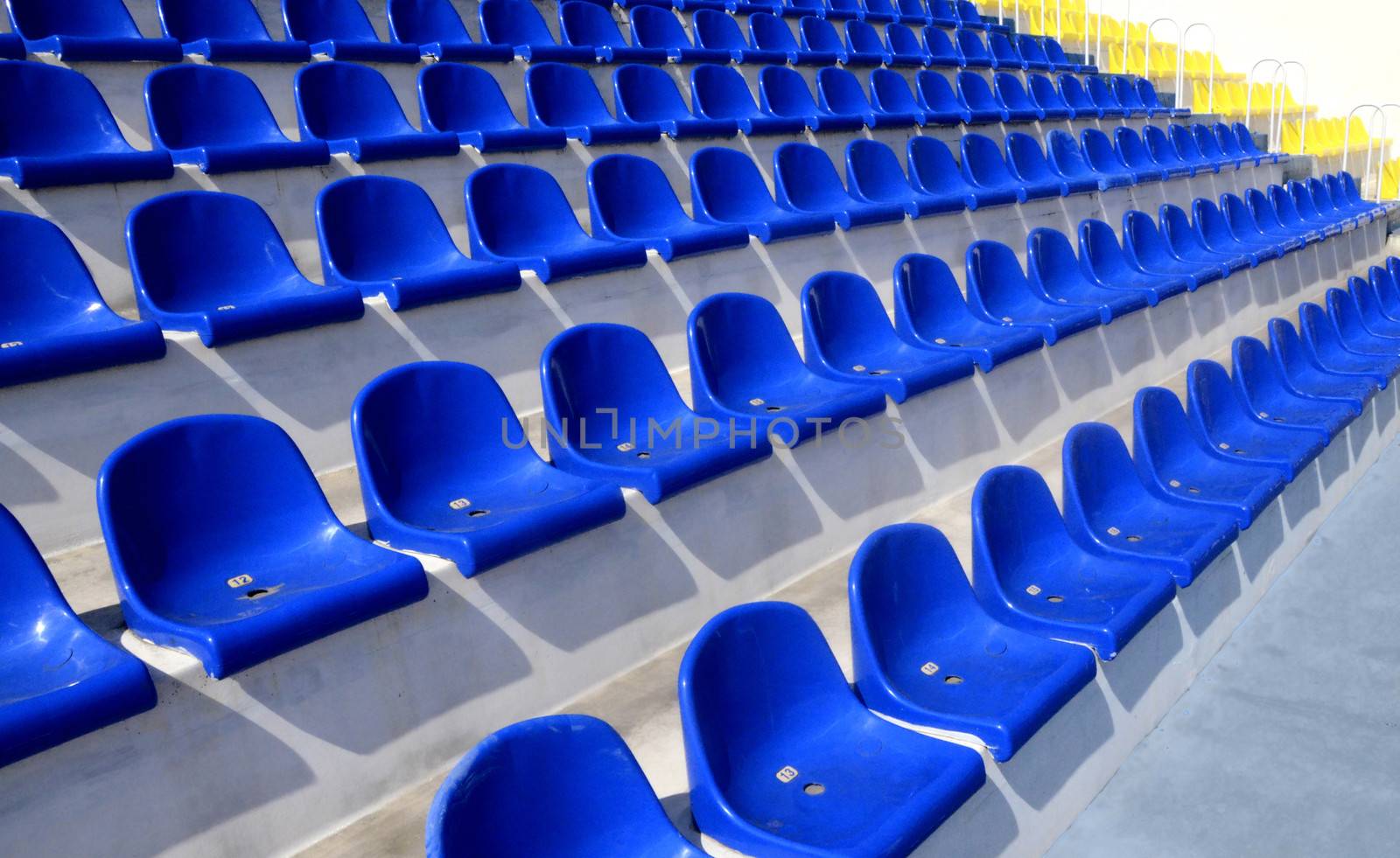 Empty plastic blue and yellow seats in a stadium 