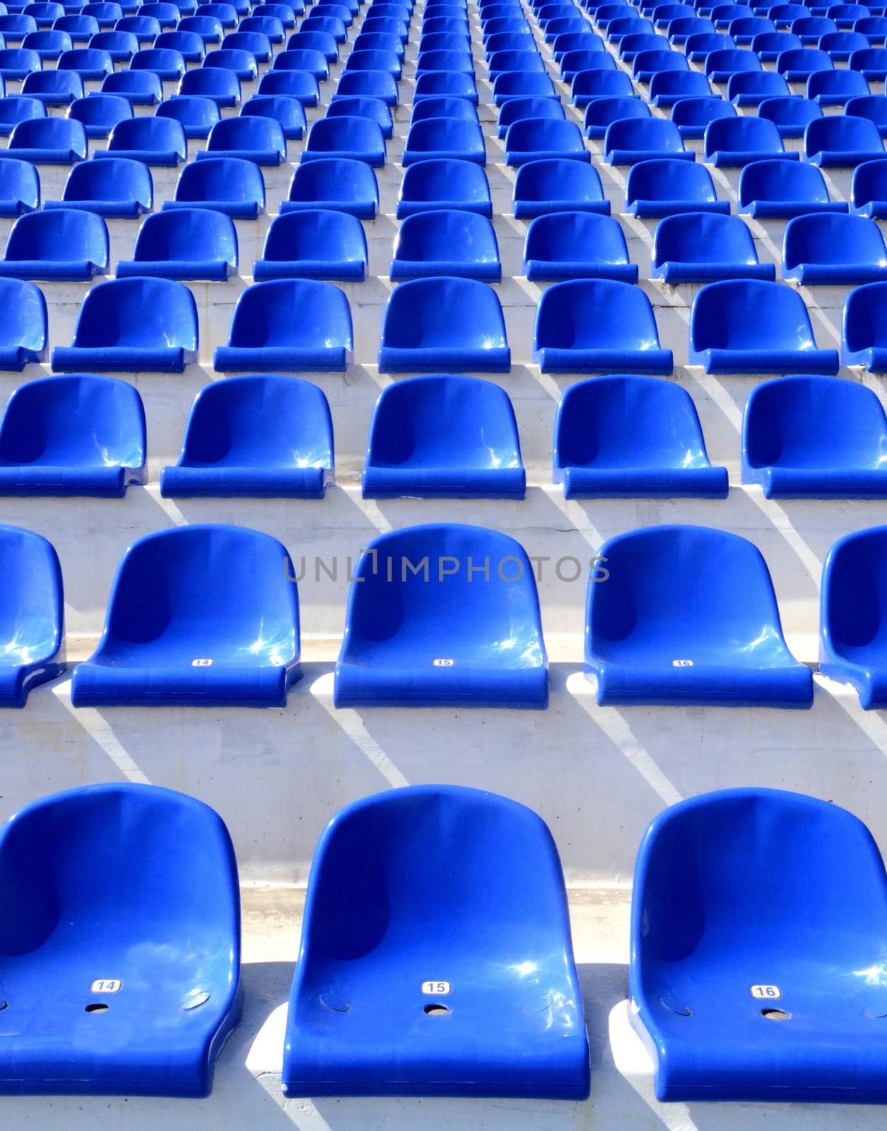 Empty blue plastic armchairs on a stadium tribune 