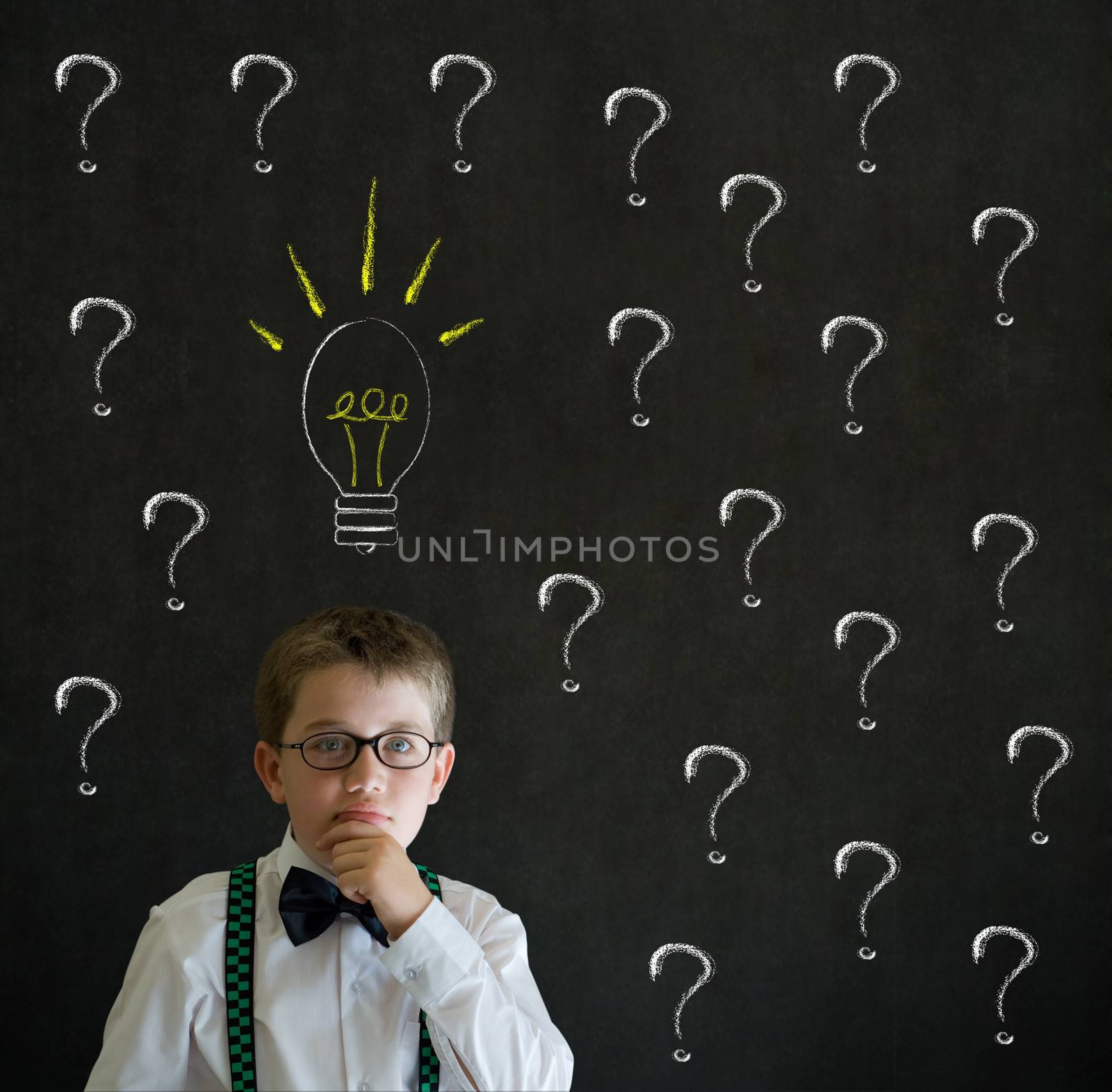 Thinking boy dressed up as business man questioning ideas on blackboard background