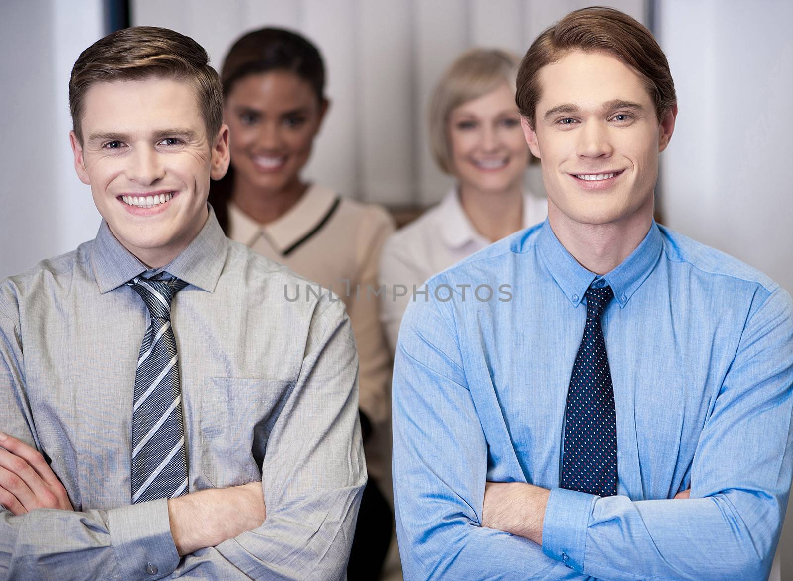 Cheerful work team posing, arms crossed. by stockyimages