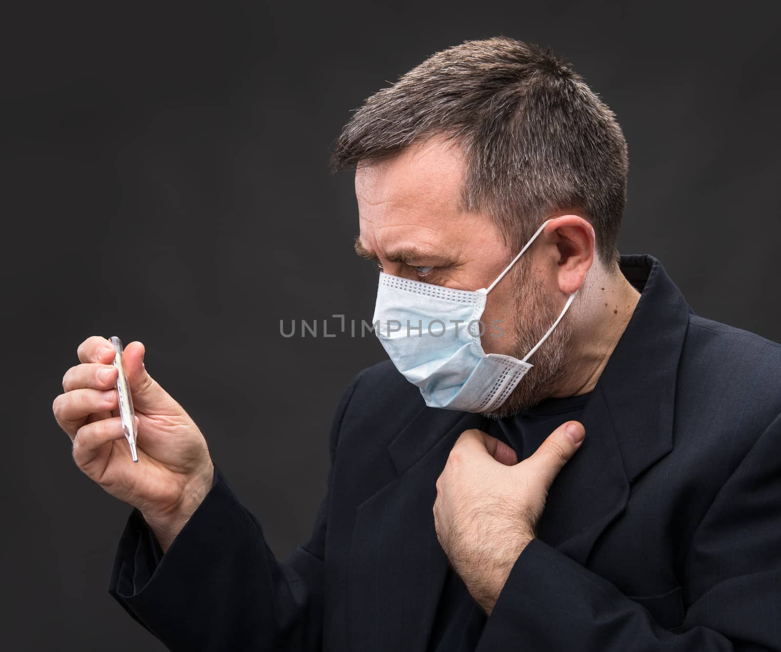 Illness. Man in medical mask with a thermometer