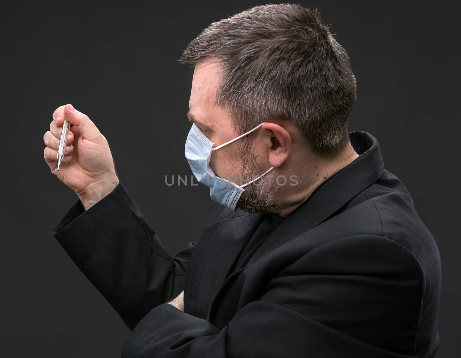 Man in medical mask with a thermometer by palinchak