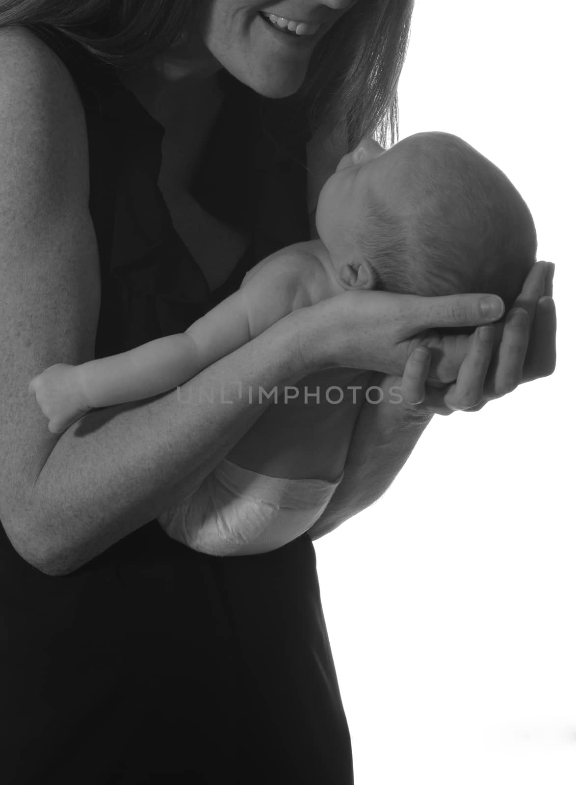 mom smiling at newborn infant and cradling baby in her arms